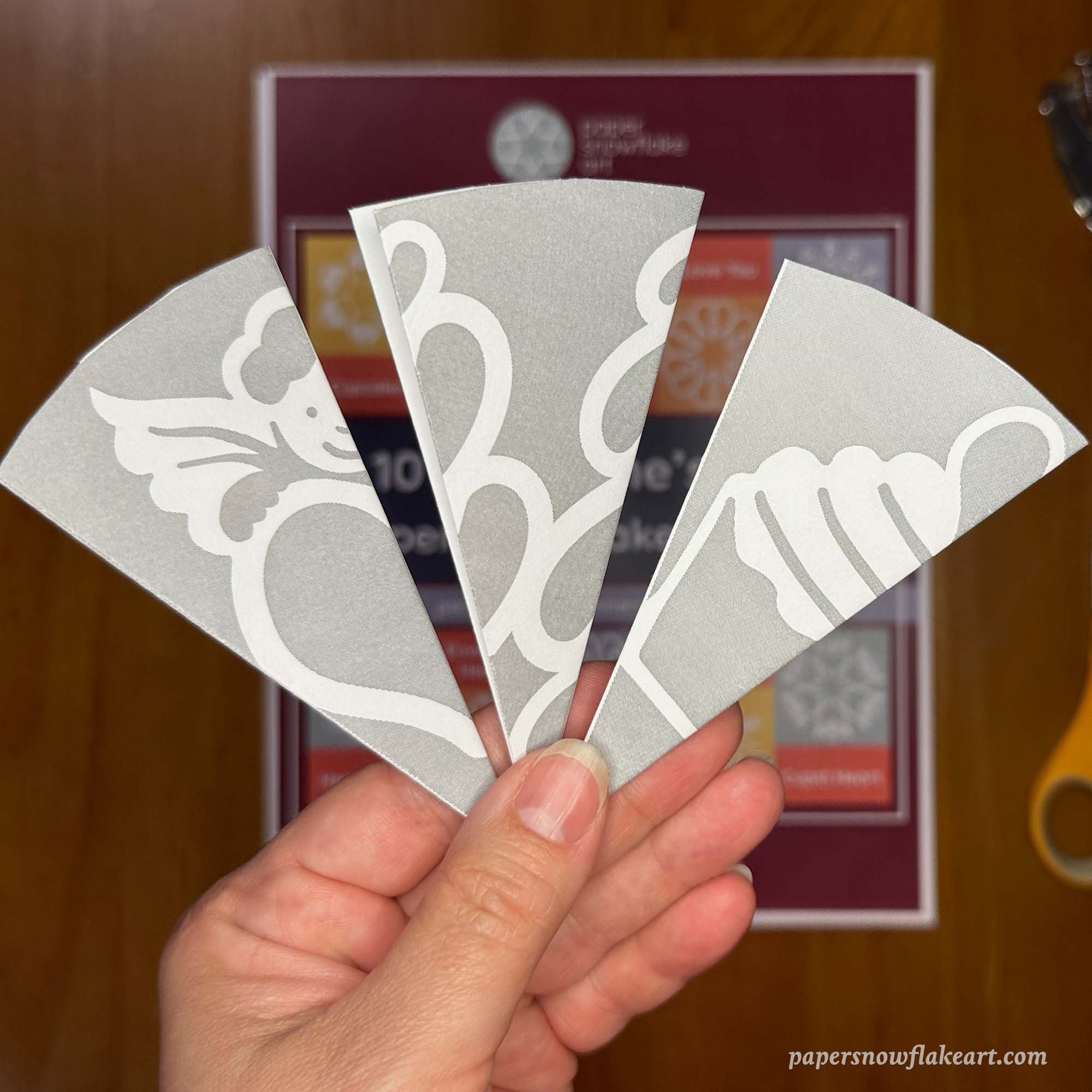 Hand holding three folded Valentine's Day paper snowflakes
