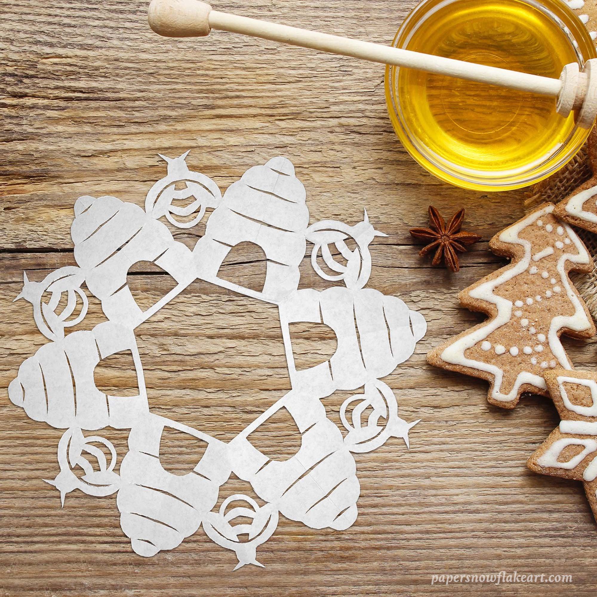 Honey bee and hive paper snowflake on a table next to a jar of honey