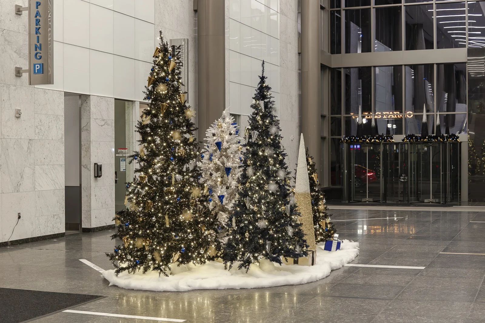 Indoor Christmas tree display in office lobby with lights and decorations.