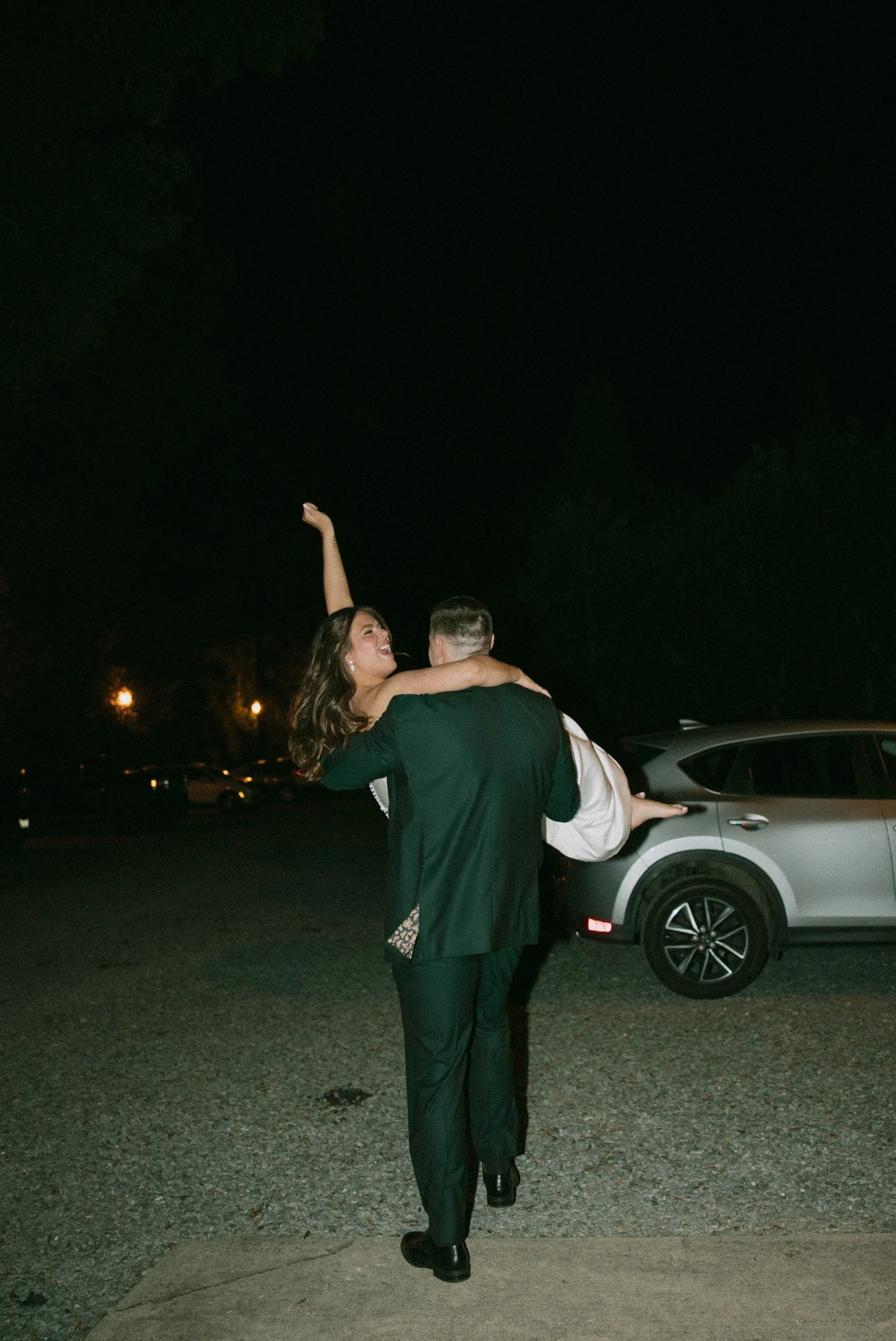 groom carrying bride in parking lot
