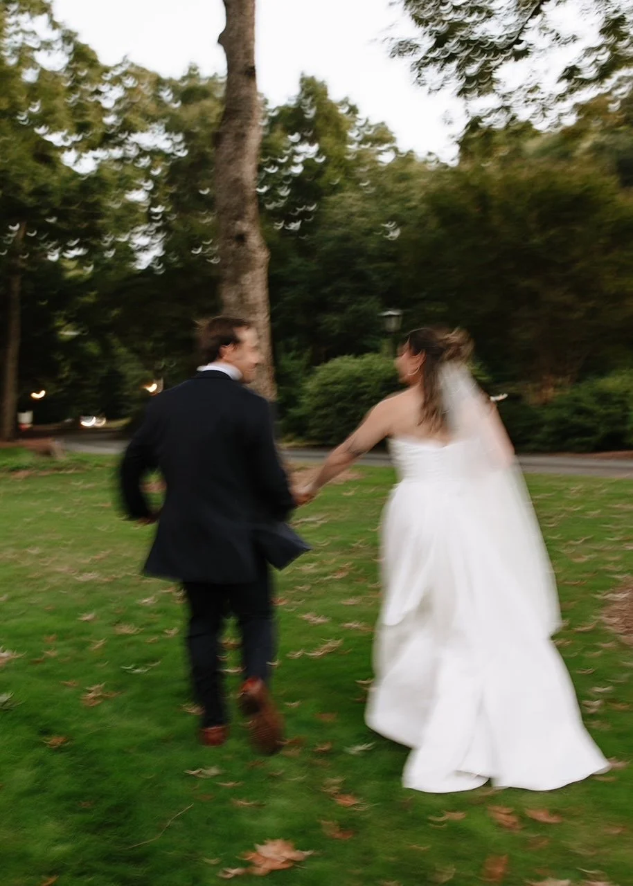 bride & groom running away from the camera on a lawn