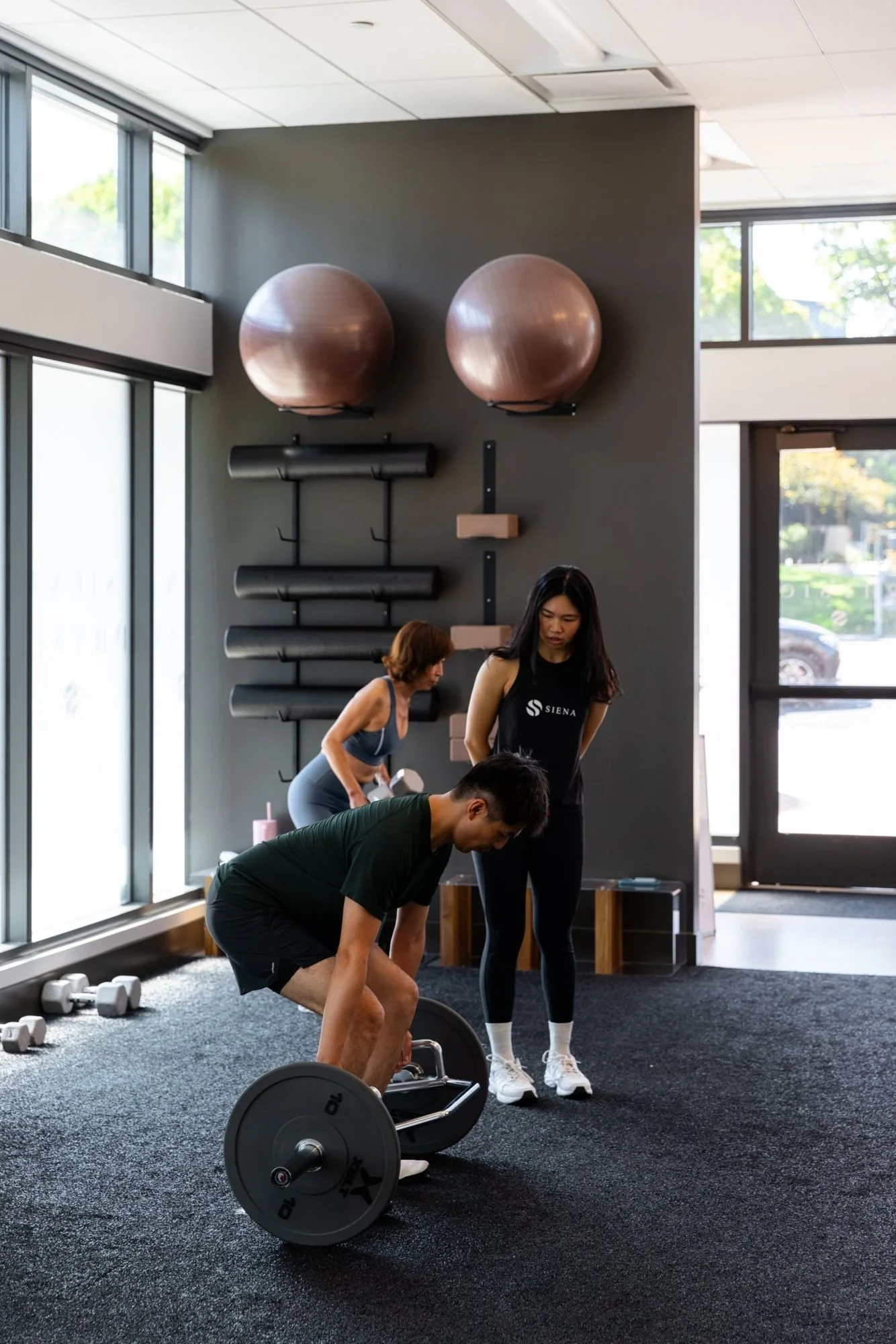 A Siena coach watches a client set up for a deadlift