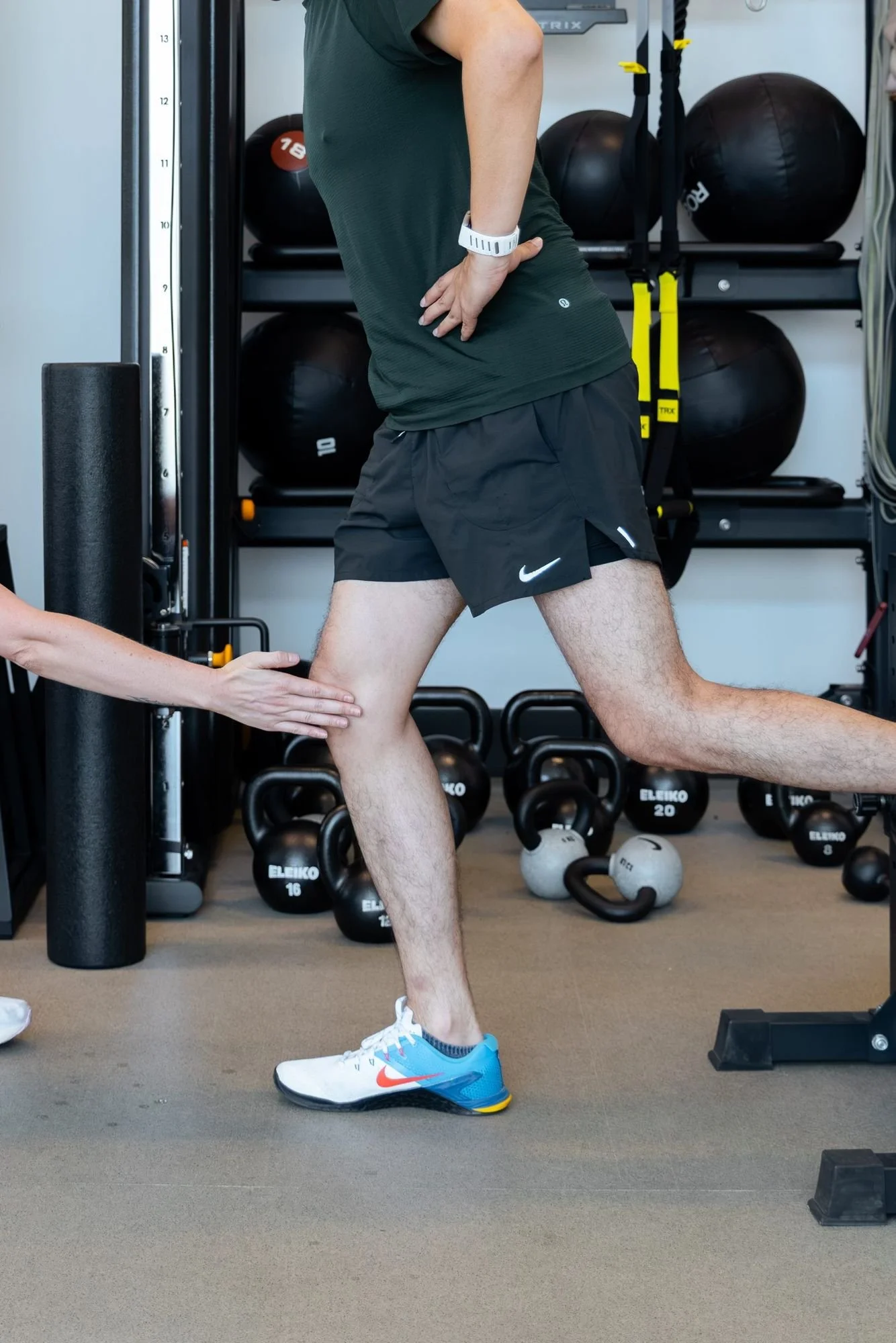 A physio cueing a client's knee during a split squat