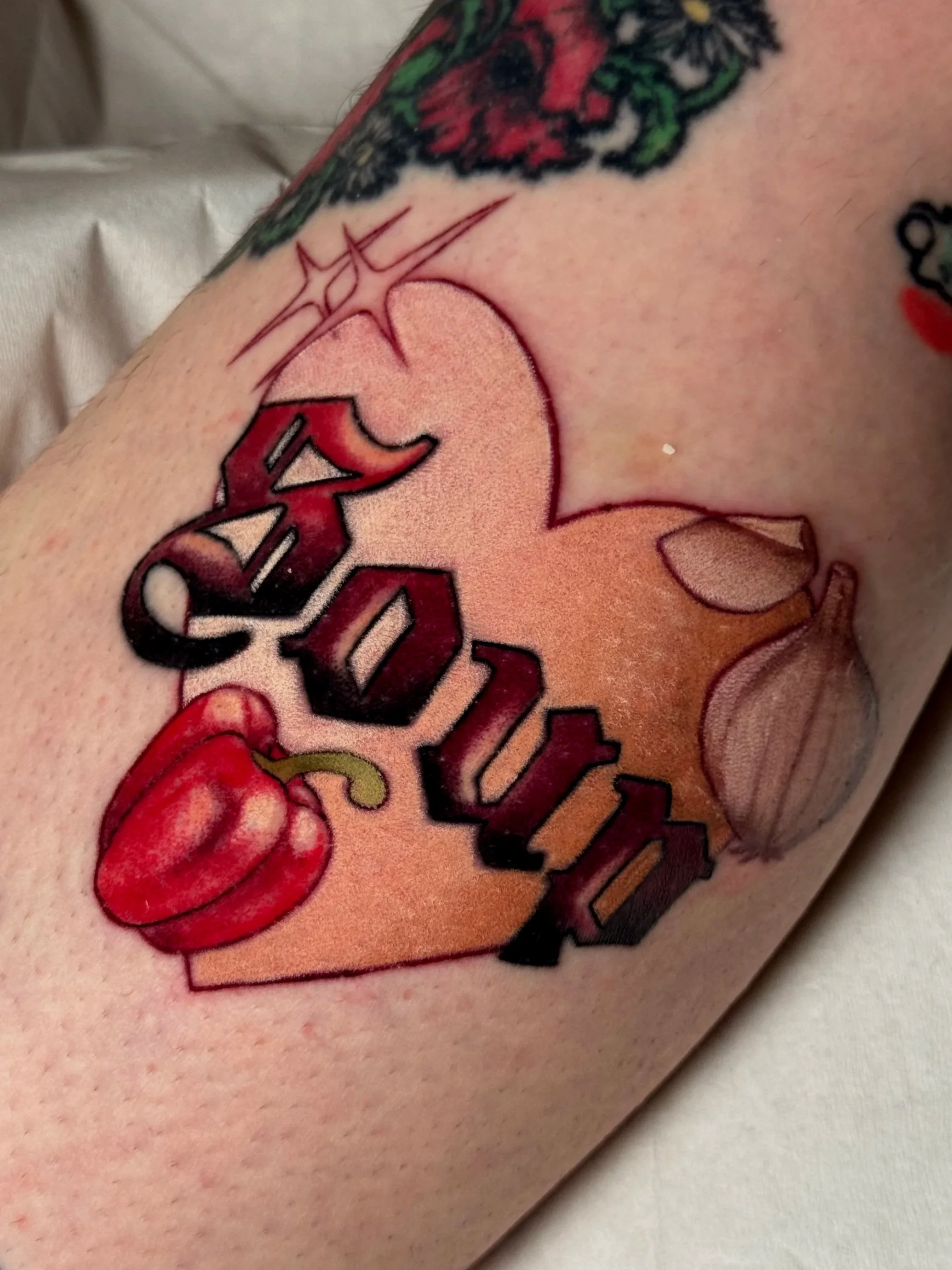 Neotraditional tattoo of soup text with garlic and bellpepper inside a heart