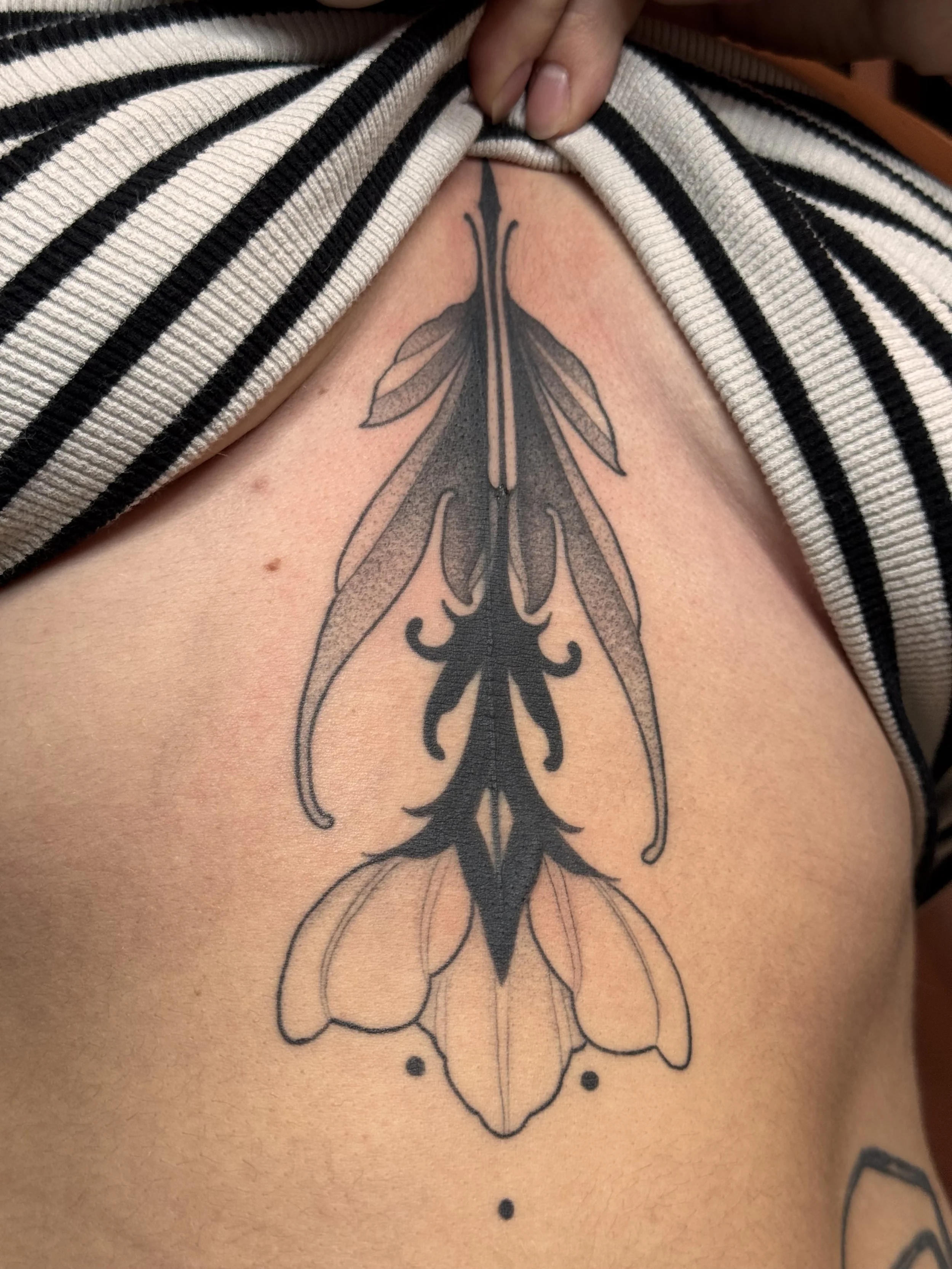 Healed cover-up tattoo of an ornamental blackwork flower sternum piece