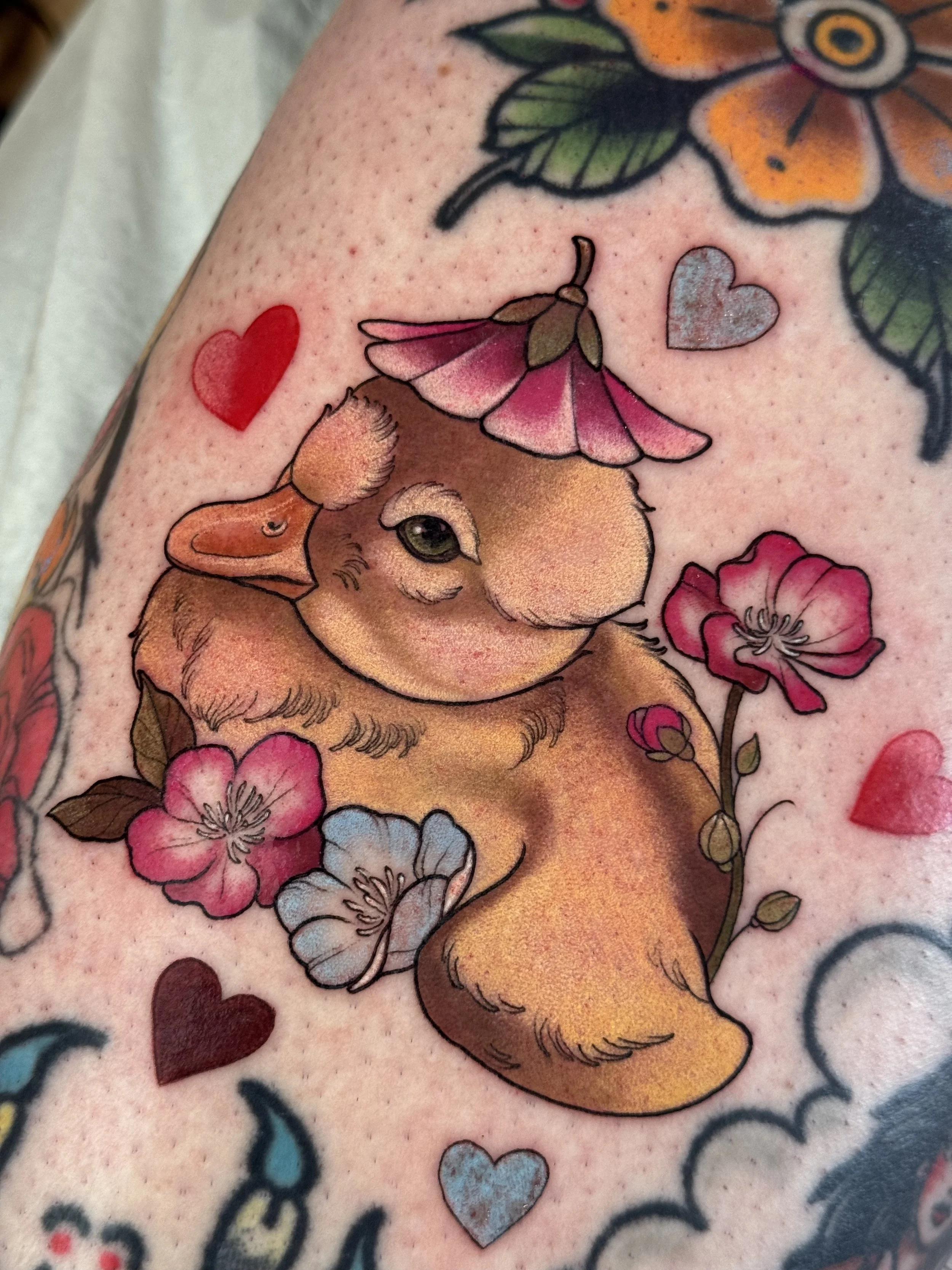 Duckling color neotraditional/illustrative tattoo with flowers and hearts