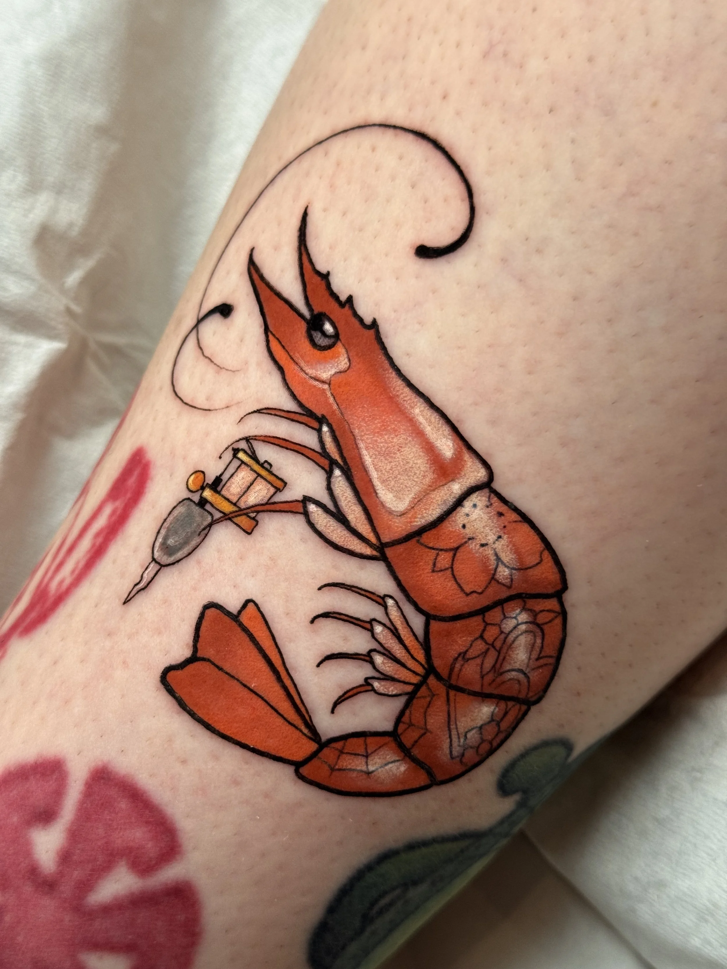 Neotraditional shrimp tattoo holding a tattoo machine
