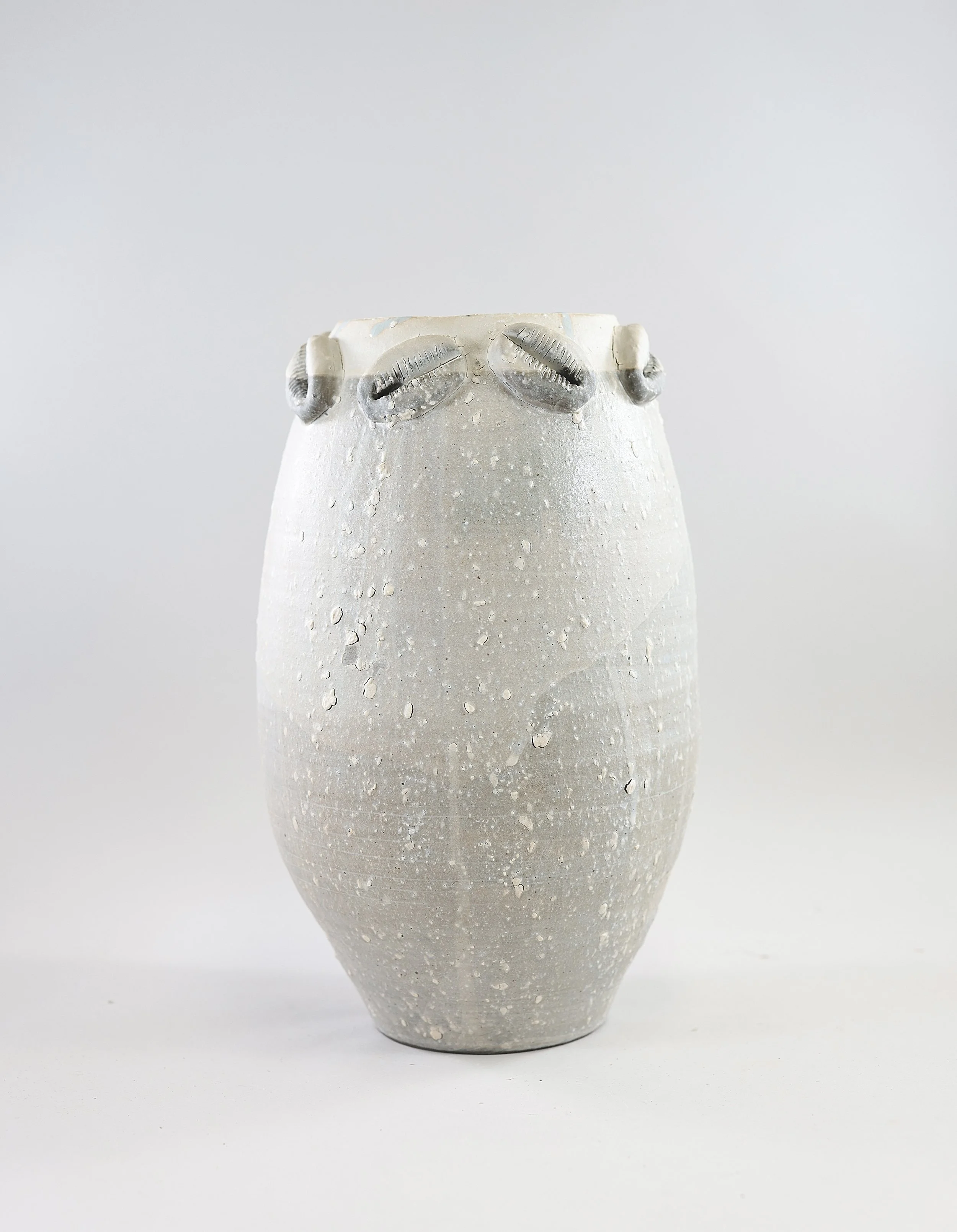 tall stoneware vessel with sculpted cowrie shells around the rim