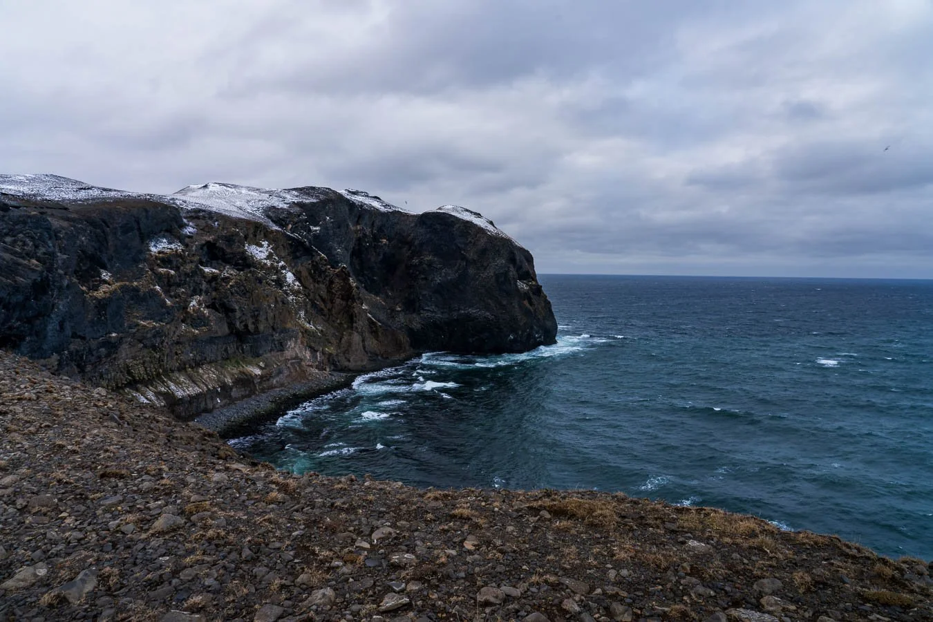 Rugged coastal cliffs overlooking the North Atlantic Ocean under a cloudy sky along Road 745 in North Iceland, a quiet and uncrowded scenic route.