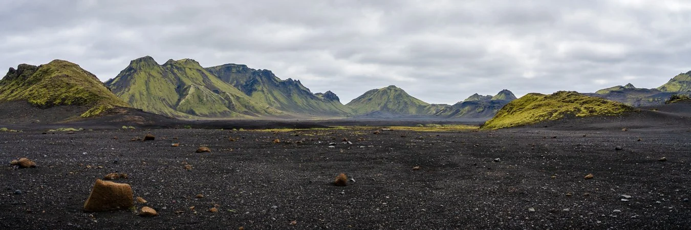 Panoramic view of moss-covered hills rising above the black glacial outwash plains along the Laugavegur trail between Emstrur and Álftavatn/Hvanngil in Iceland’s Highlands.