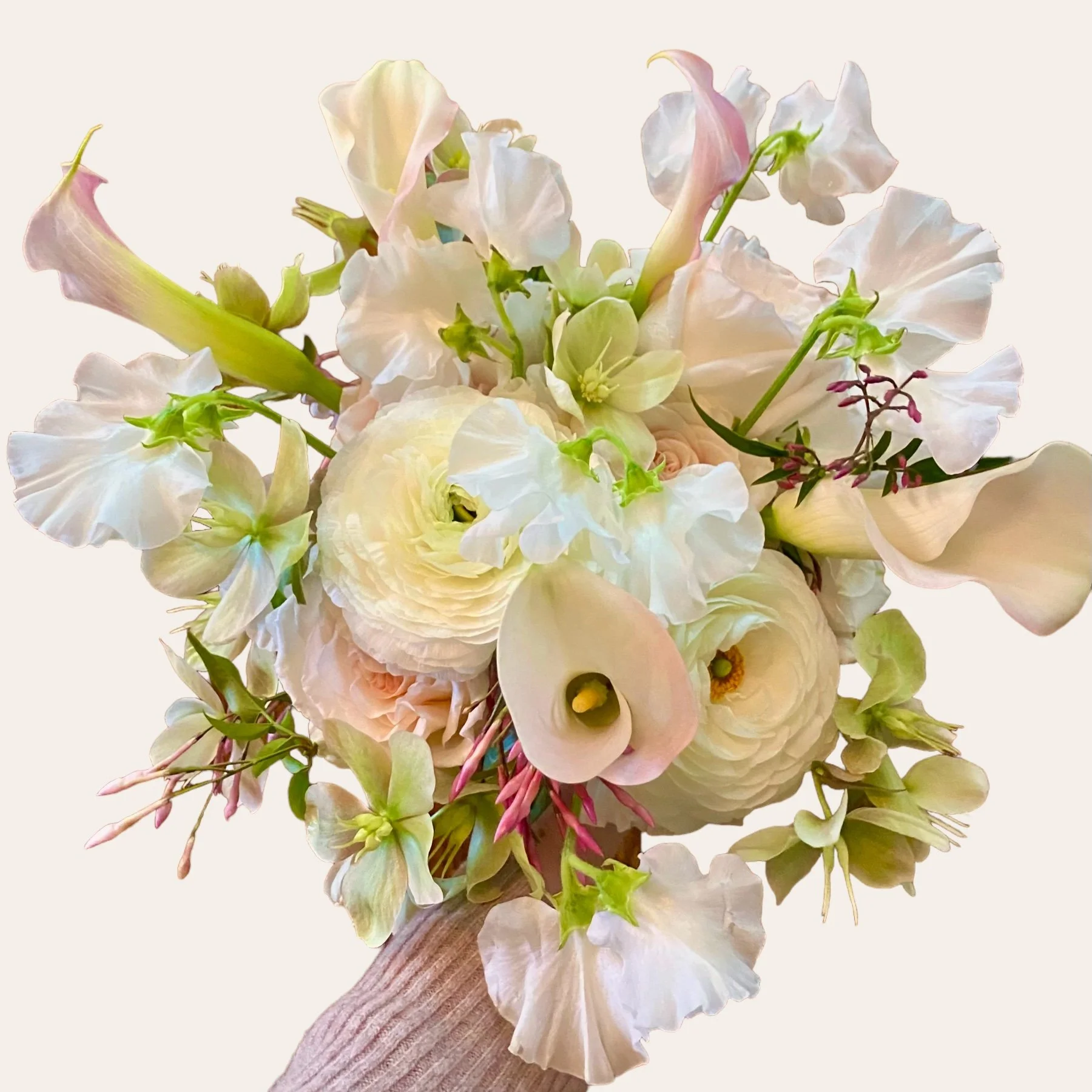 A bouquet of pastel-colored flowers, including white and pale peach roses, calla lilies, and greenery, arranged against a plain white background.