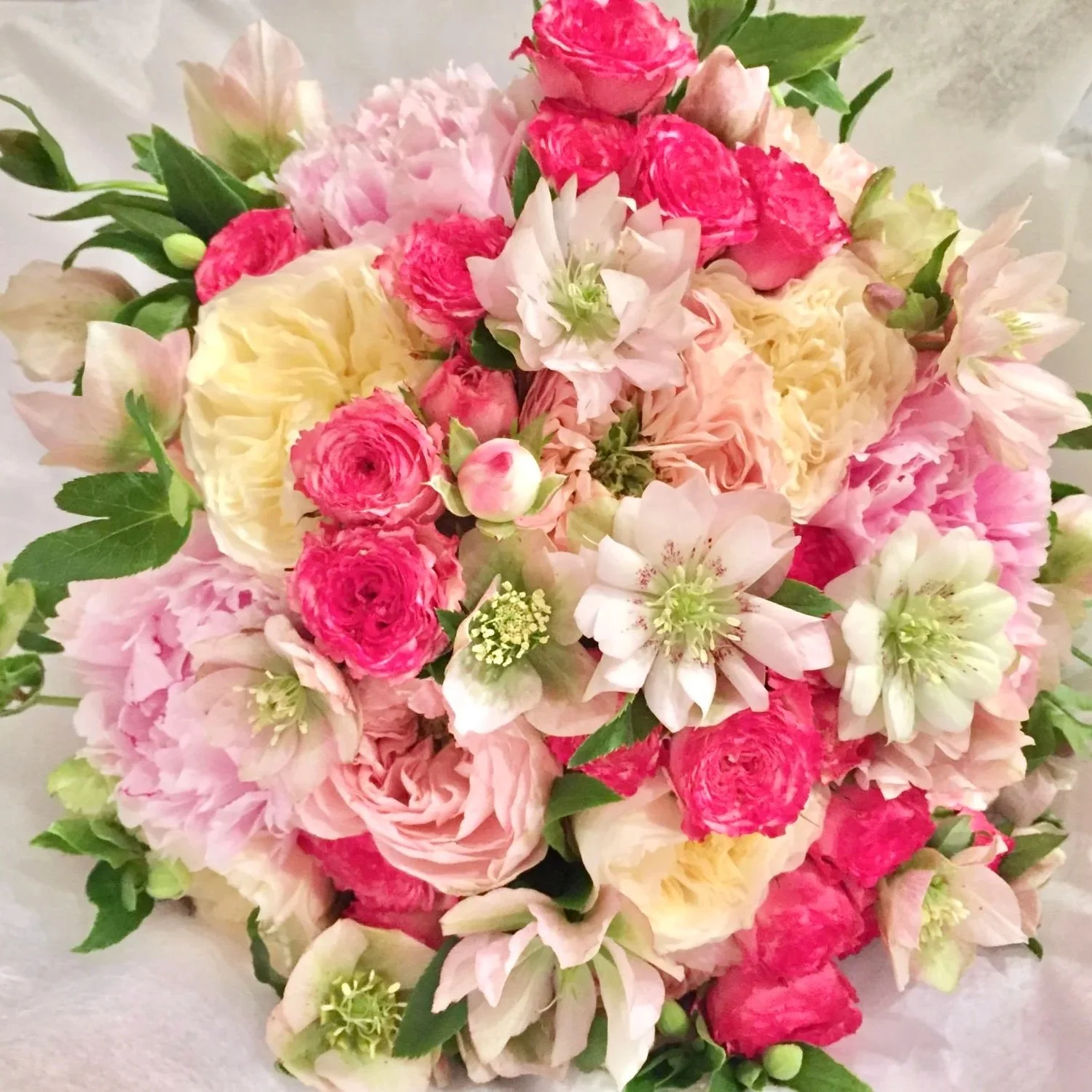 A bouquet of assorted pink and white flowers with green leaves