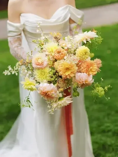 A bride holding a large bouquet of flowers in a garden setting.