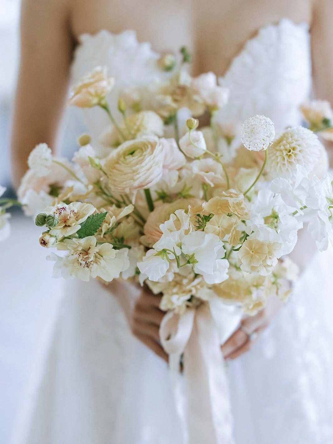 Bride holding a bouquet of white and cream flowers.