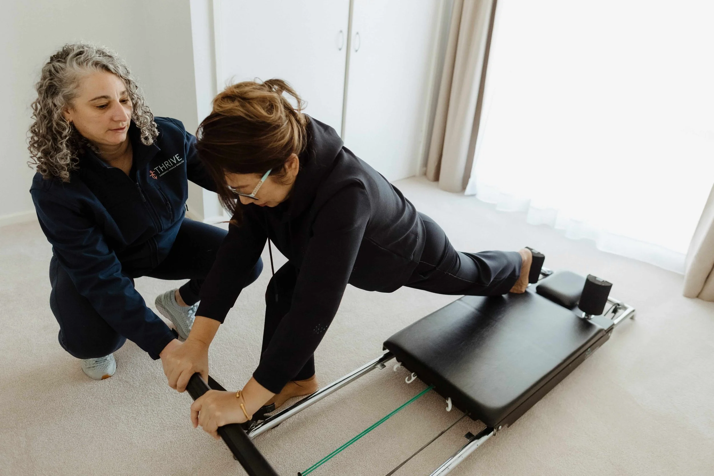 Home physiotherapist supporting an older adult with exercise