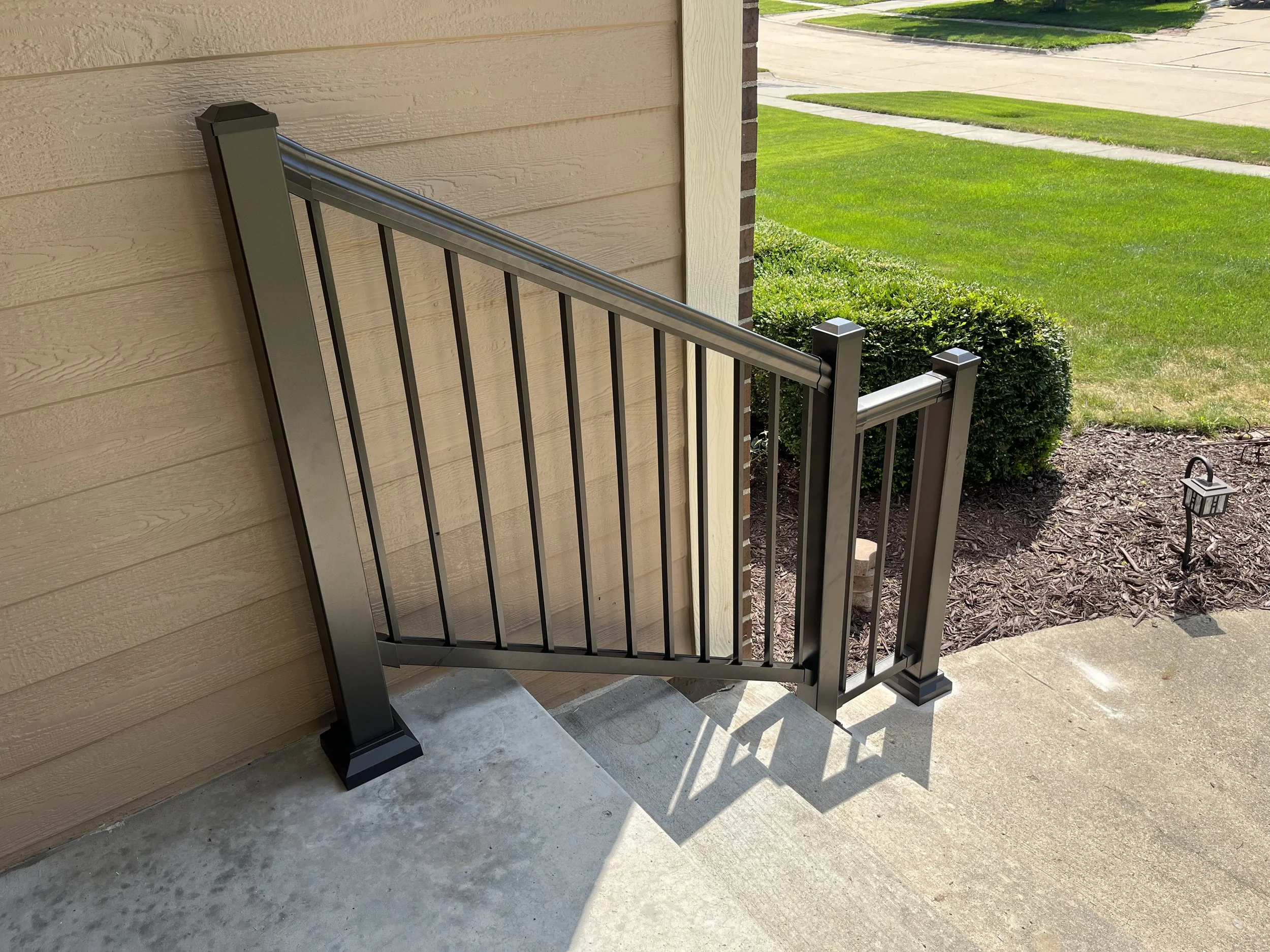 Bronze aluminum handrail installed in Ankeny, IA on the front steps of a residential home, providing safe access with a clean, understated appearance.