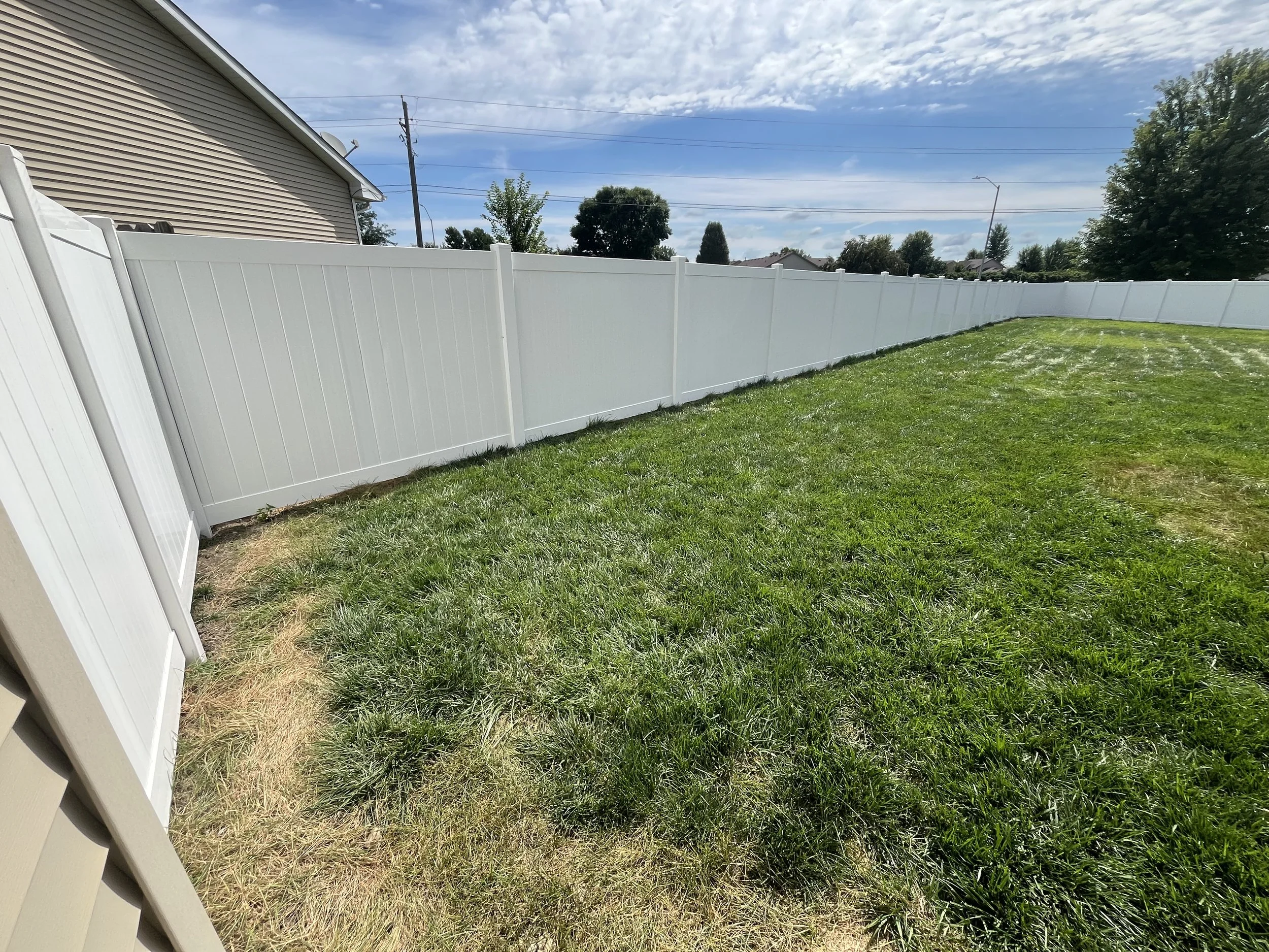 White vinyl fence installed in Ankeny, Iowa, enclosing a large yard as part of a larger residential fencing project. This installation provides privacy, durability, and a clean, uniform appearance.