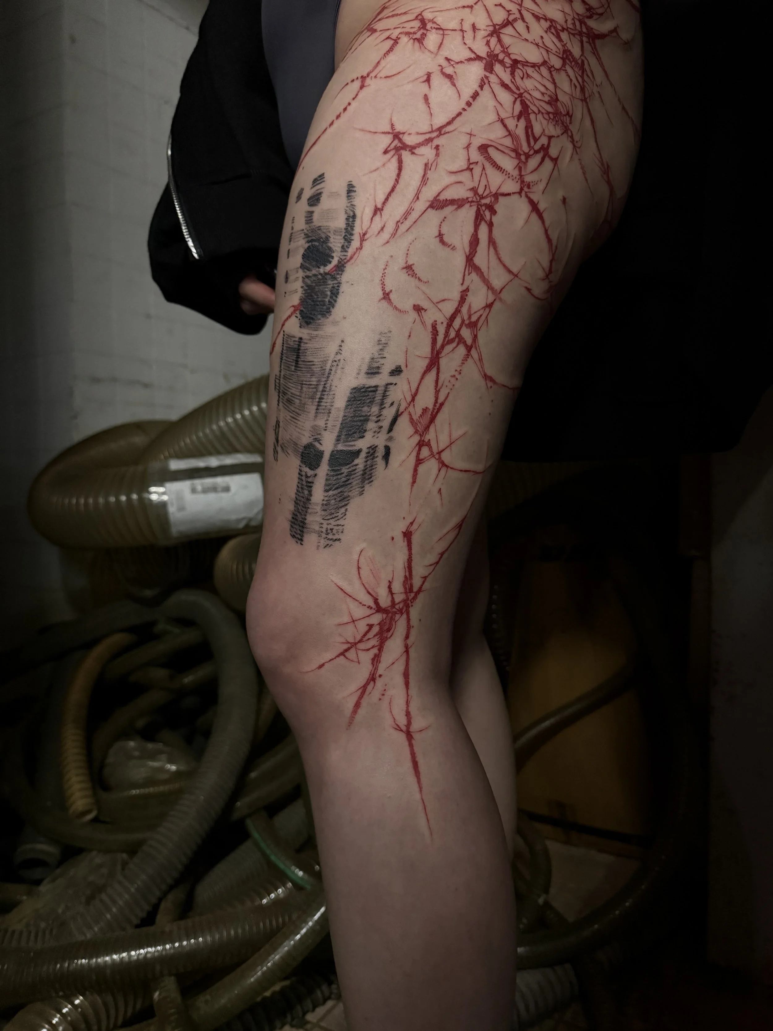 A person's leg with fresh red scratch marks and a black barcode tattoo.