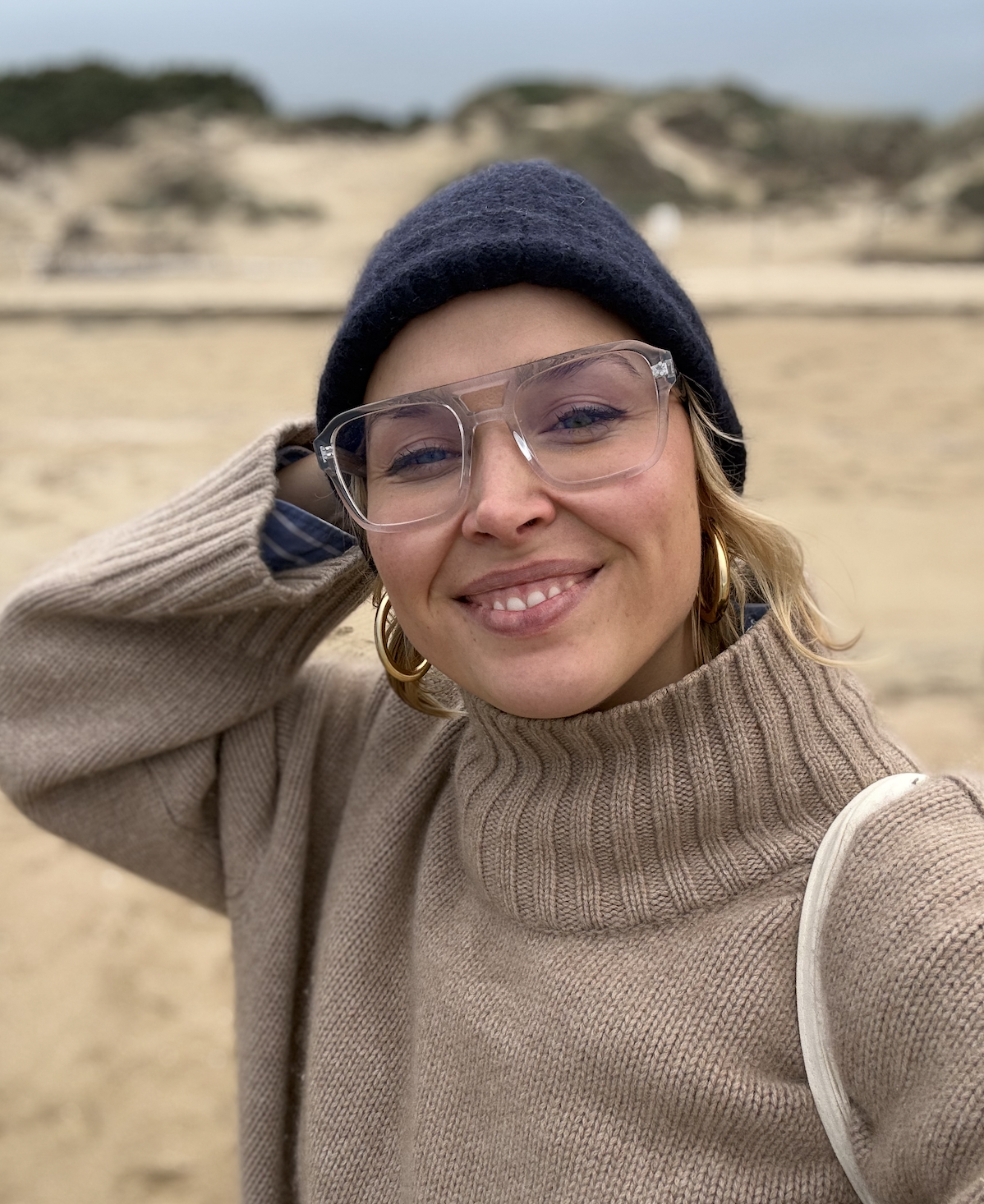 bild von frau mit mütze und brille am strand