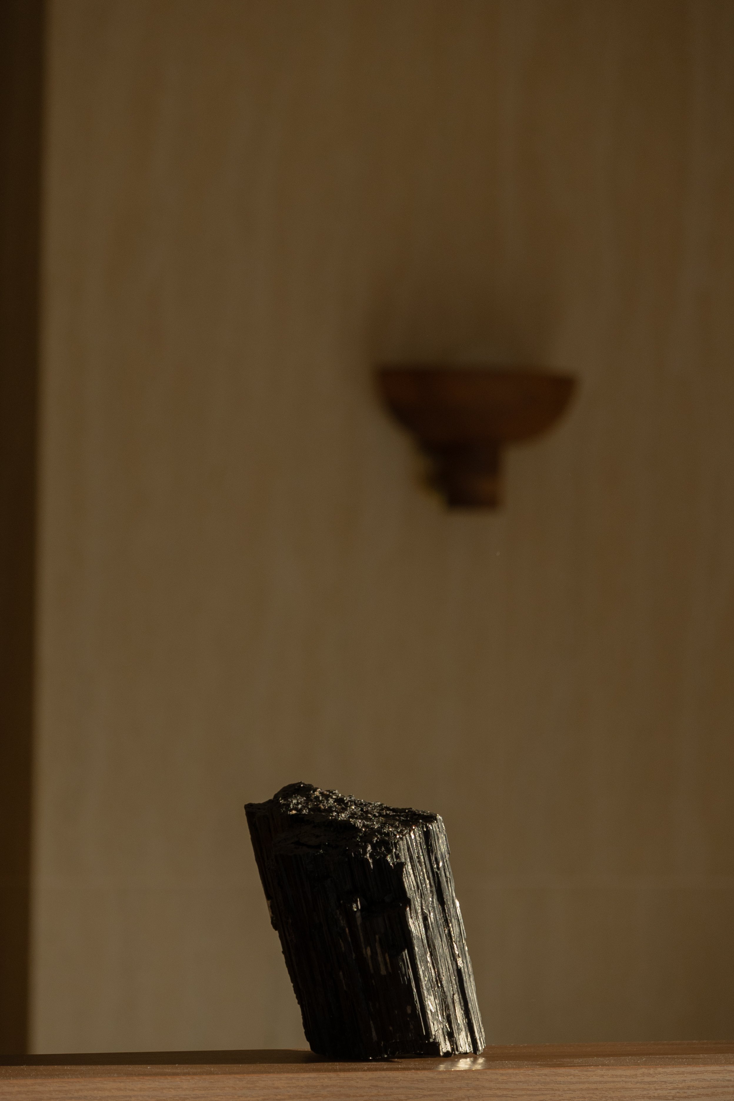Wood wall with table holding a tall black crystal, reflecting a healer’s workspace supported by virtual assistant services for digital product launches, content marketing, SEO, and admin.