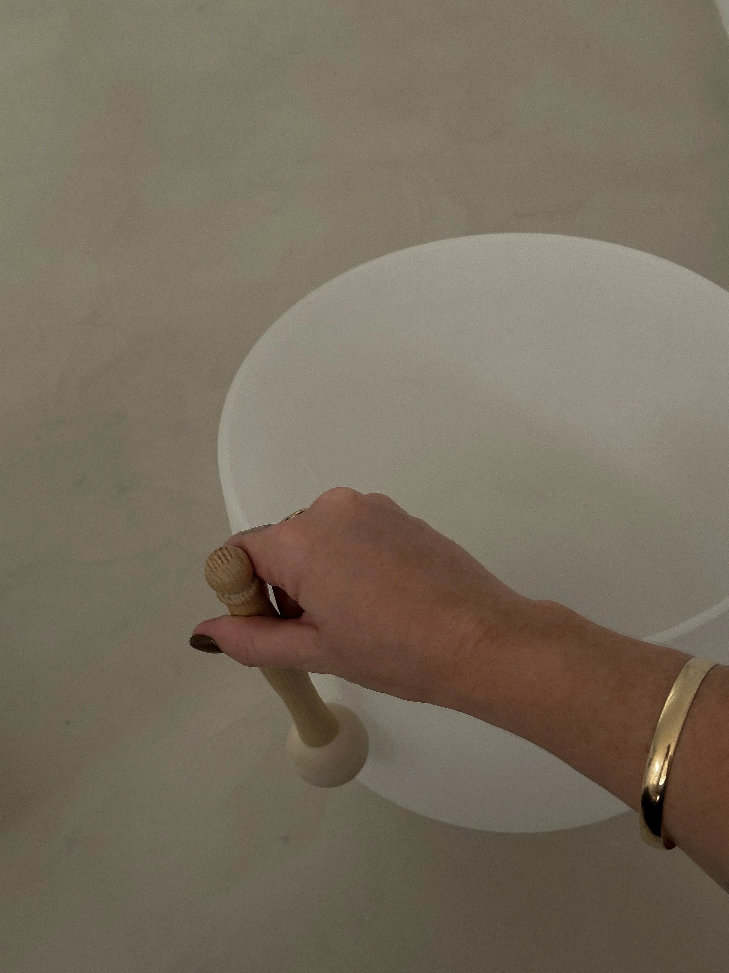 woman's hand playing a sound bath bowl, symbolizing the hands-on wellness expertise that health coaches translate into transformative online courses and memberships with specialized VA support