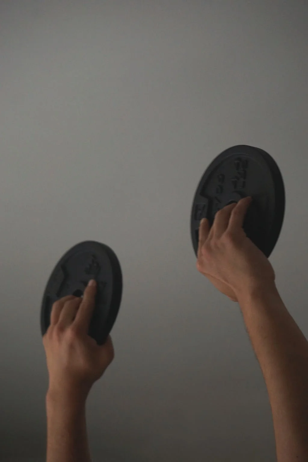 Two hands each lifting a black weighted disc in a personal trainer studio, representing fitness content created with virtual assistant support for digital product launches, content marketing, SEO, and admin services for movement-based professionals