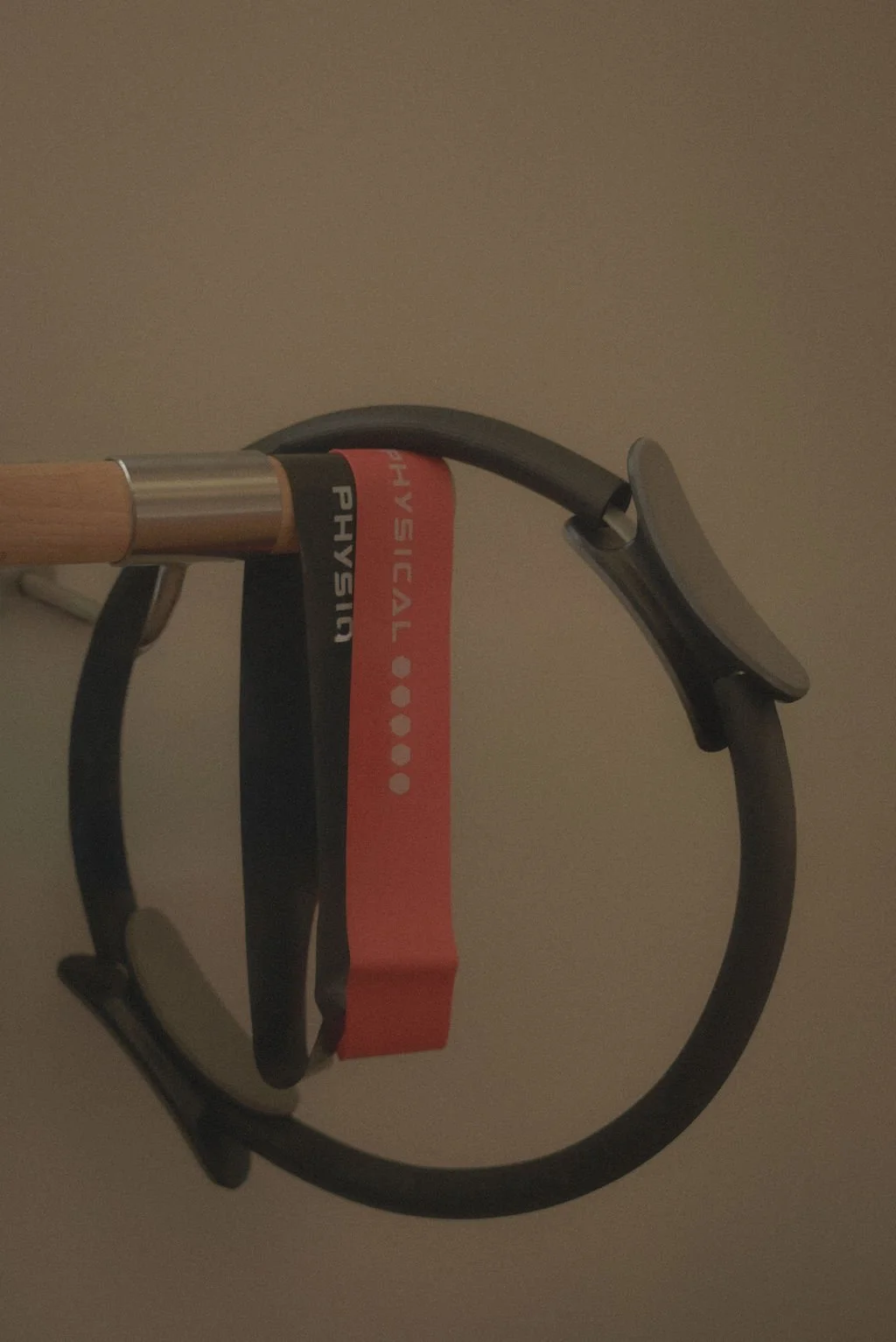 Wooden bar in a personal trainer studio with a black Pilates circle and two resistance bands hanging on it, representing fitness content created with virtual assistant support for digital product launches, content marketing, SEO, and admin services f