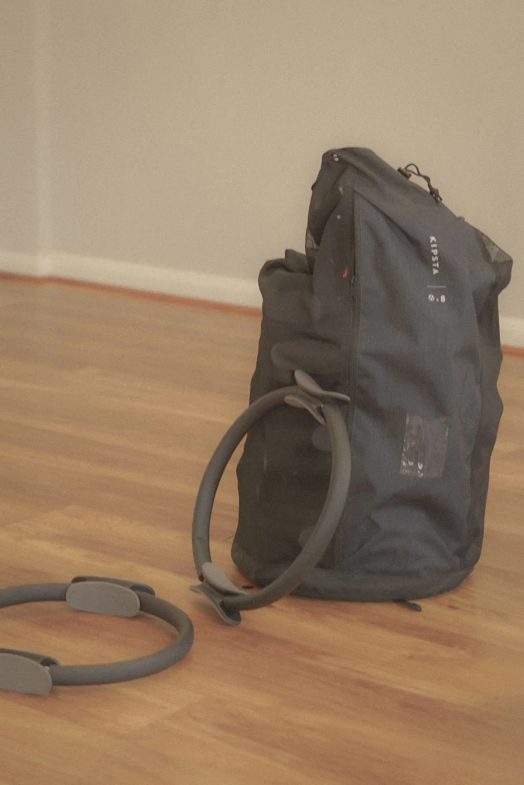 Personal trainer studio with white wall and wooden floor, featuring a black gym bag and two black Pilates circles, representing fitness content created with virtual assistant support for digital product launches, content marketing, SEO, and admin ser