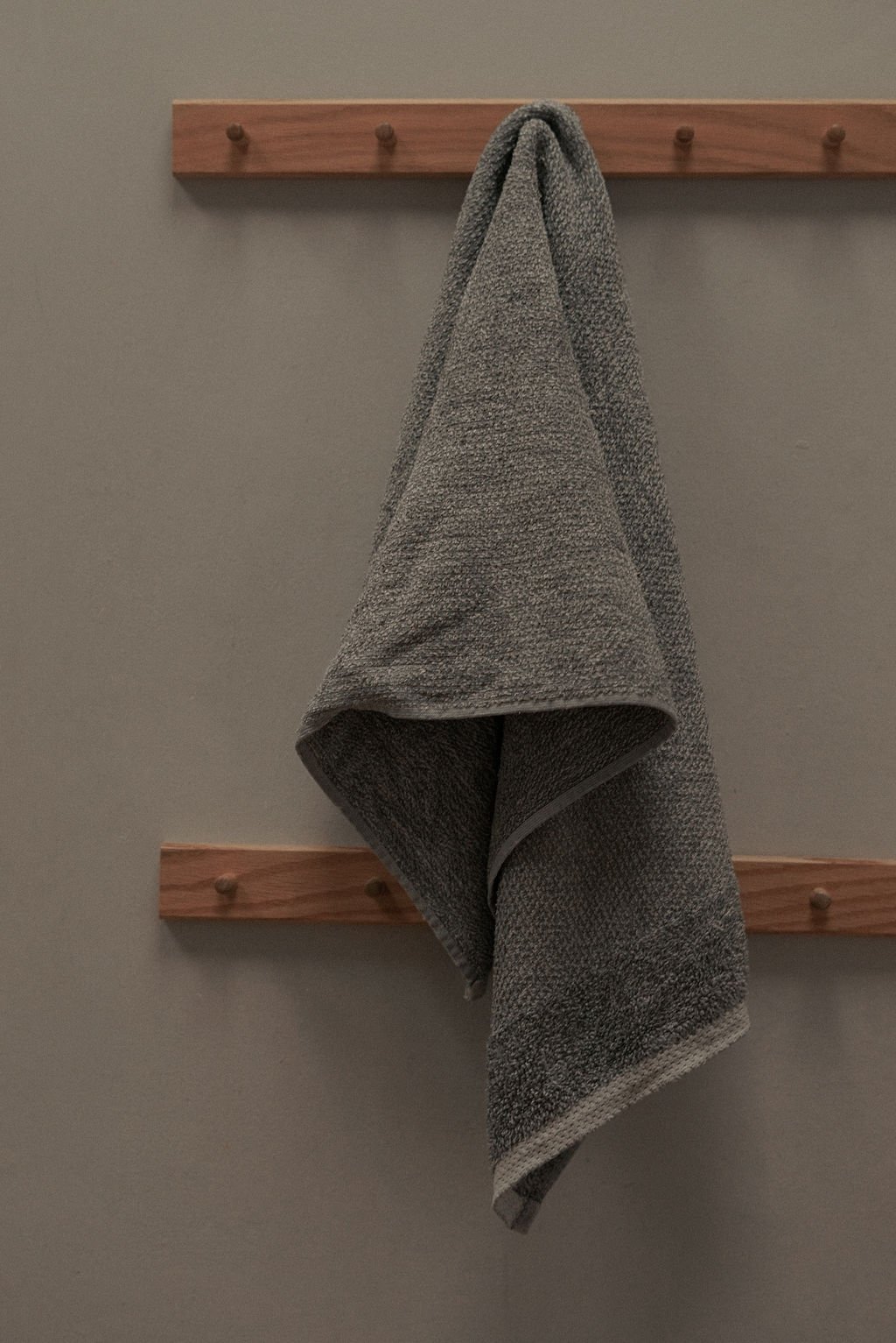 Wooden hooks holding a grey gym towel, representing fitness content and virtual assistant support for movement-based professionals