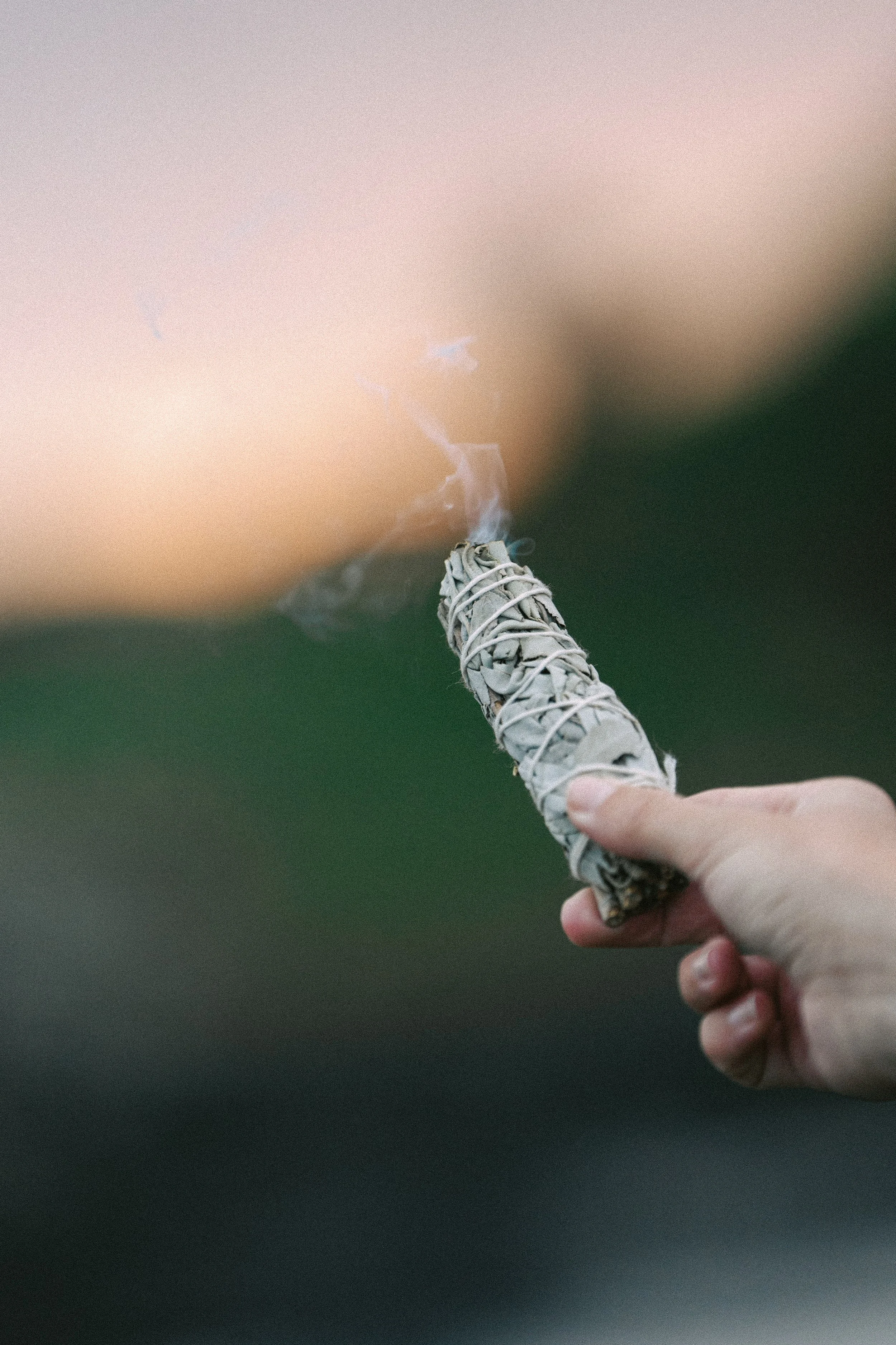 hand holding a burning sage bundle, symbolizing the ritualistic care and intentionality that goes into content marketing and SEO copywriting for somatic coaches, energy healers, and holistic wellness entrepreneurs