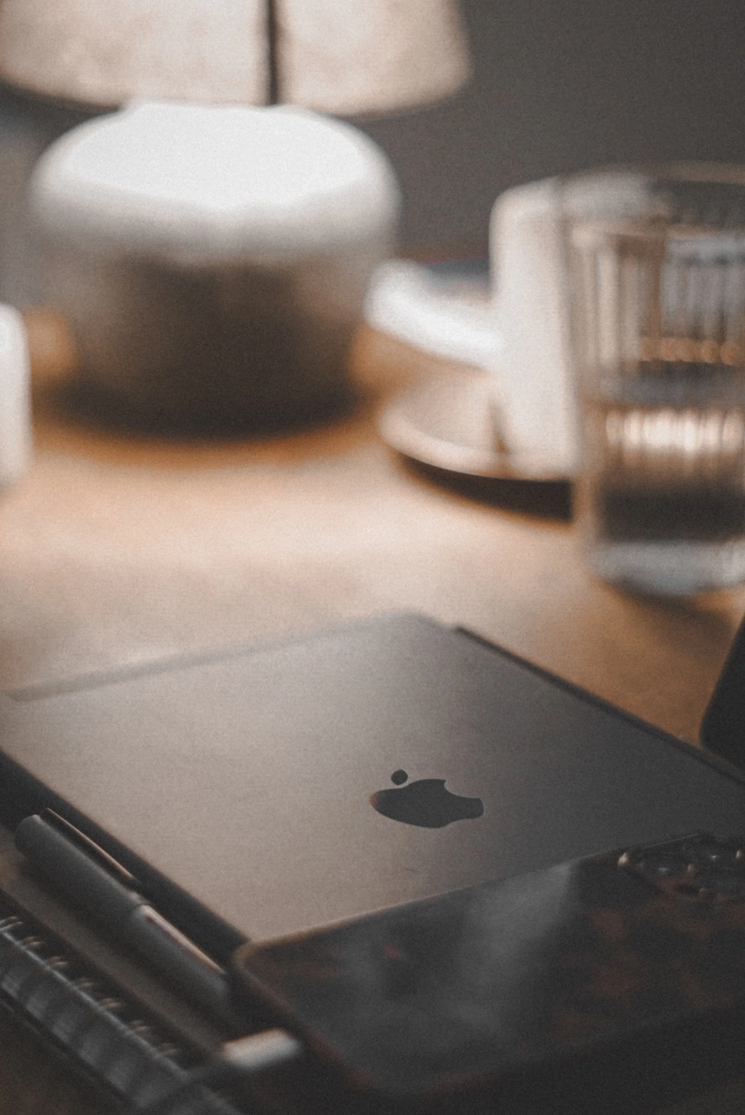 Wooden desktop with short desk lamp, glass of water, notebook, black iPad, and iPhone on top, representing wellness content for a therapist with virtual assistant support for digital product launches, content marketing, SEO, and admin
