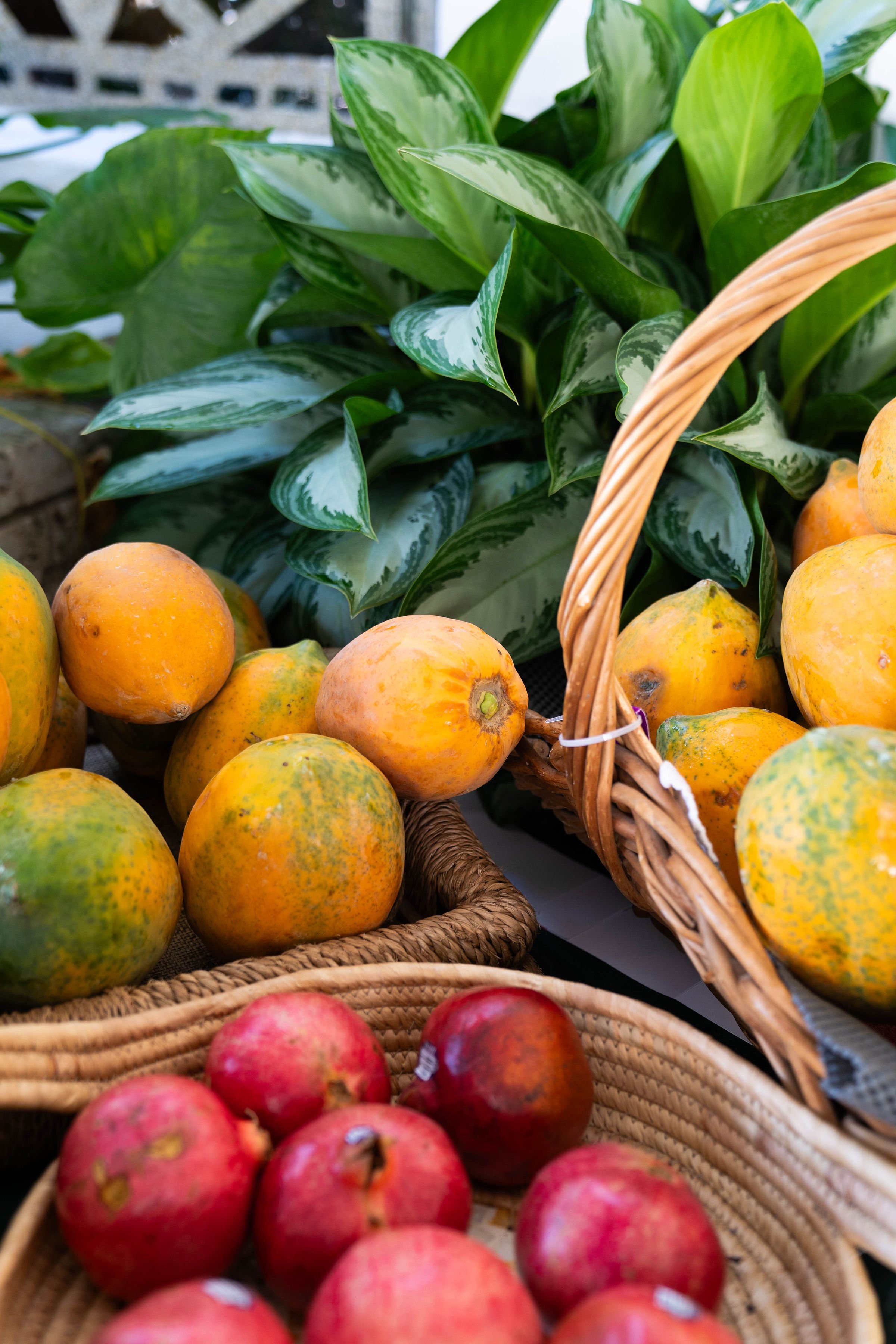 Fresh pomegranates and mangoes in woven baskets, featured on a nutritionist website offering virtual assistant support for content marketing, admin tasks, and SEO.