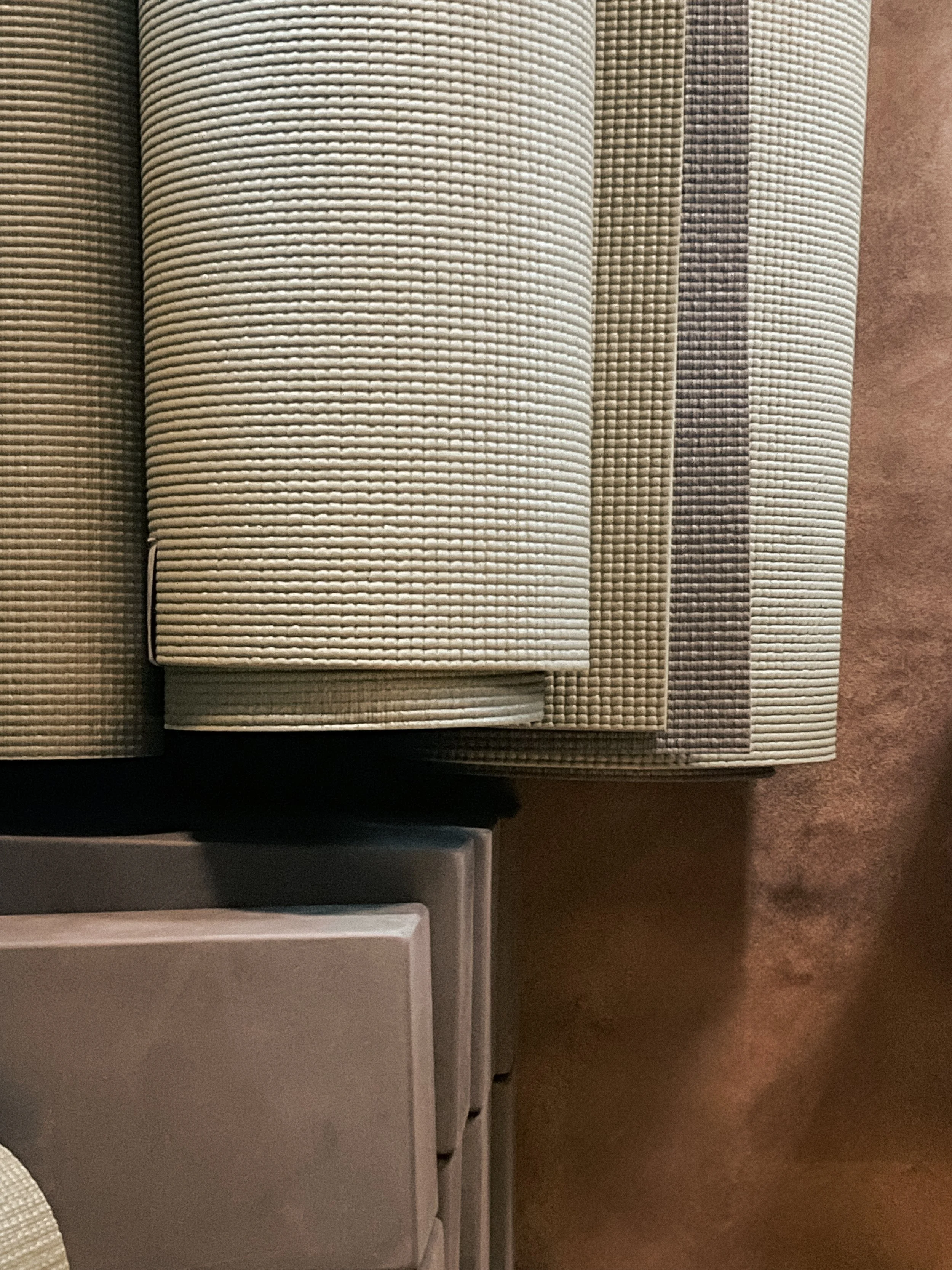 Stacked neutral-colored yoga mats with matching yoga bolsters in a studio, symbolizing wellness content created with virtual assistant support for digital products and SEO