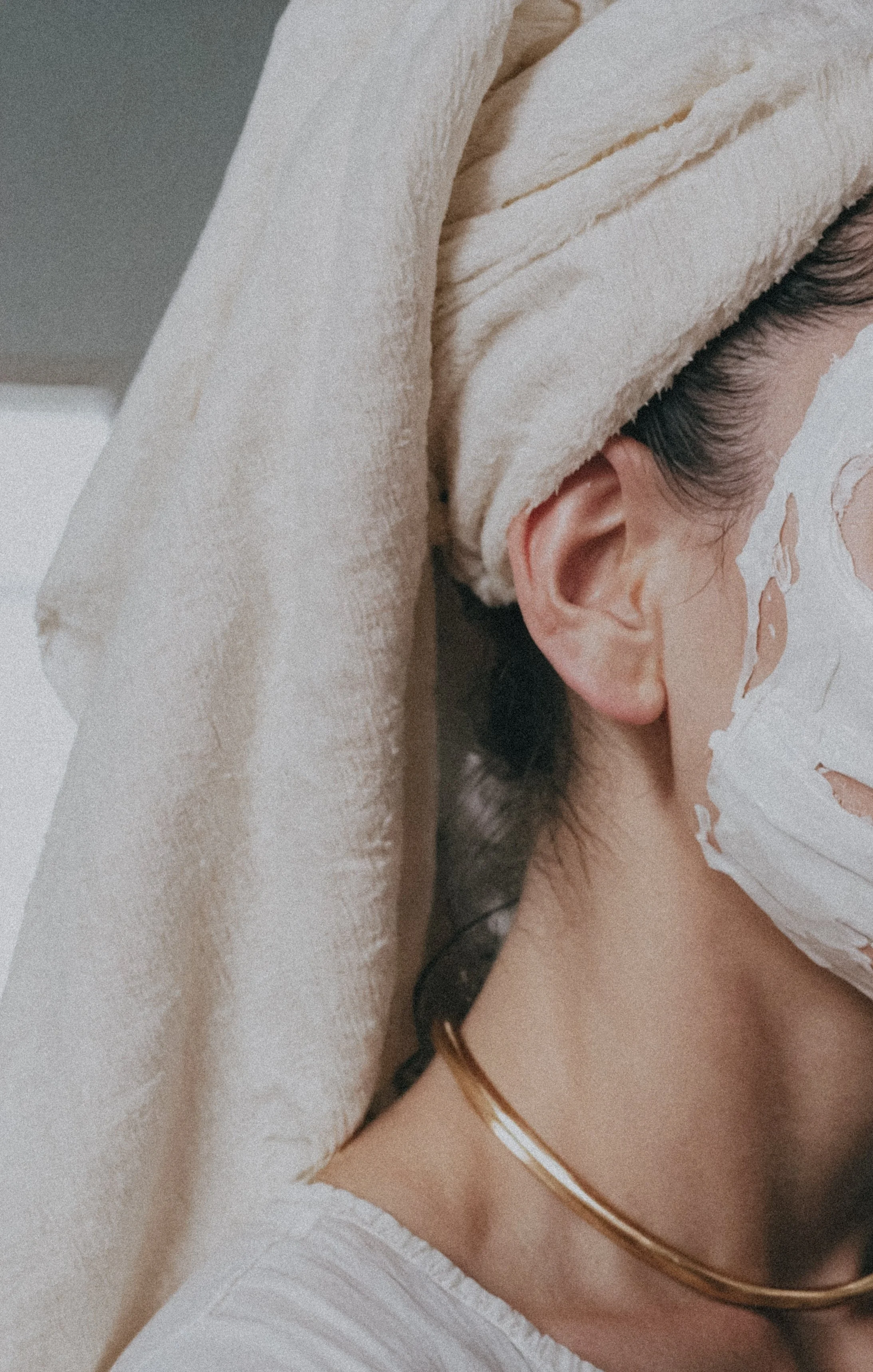 Woman with a face mask on and hair wrapped in a white towel during a spa treatment, reflecting a healer supported by a virtual assistant for digital launches, content marketing, SEO, and admin services.
