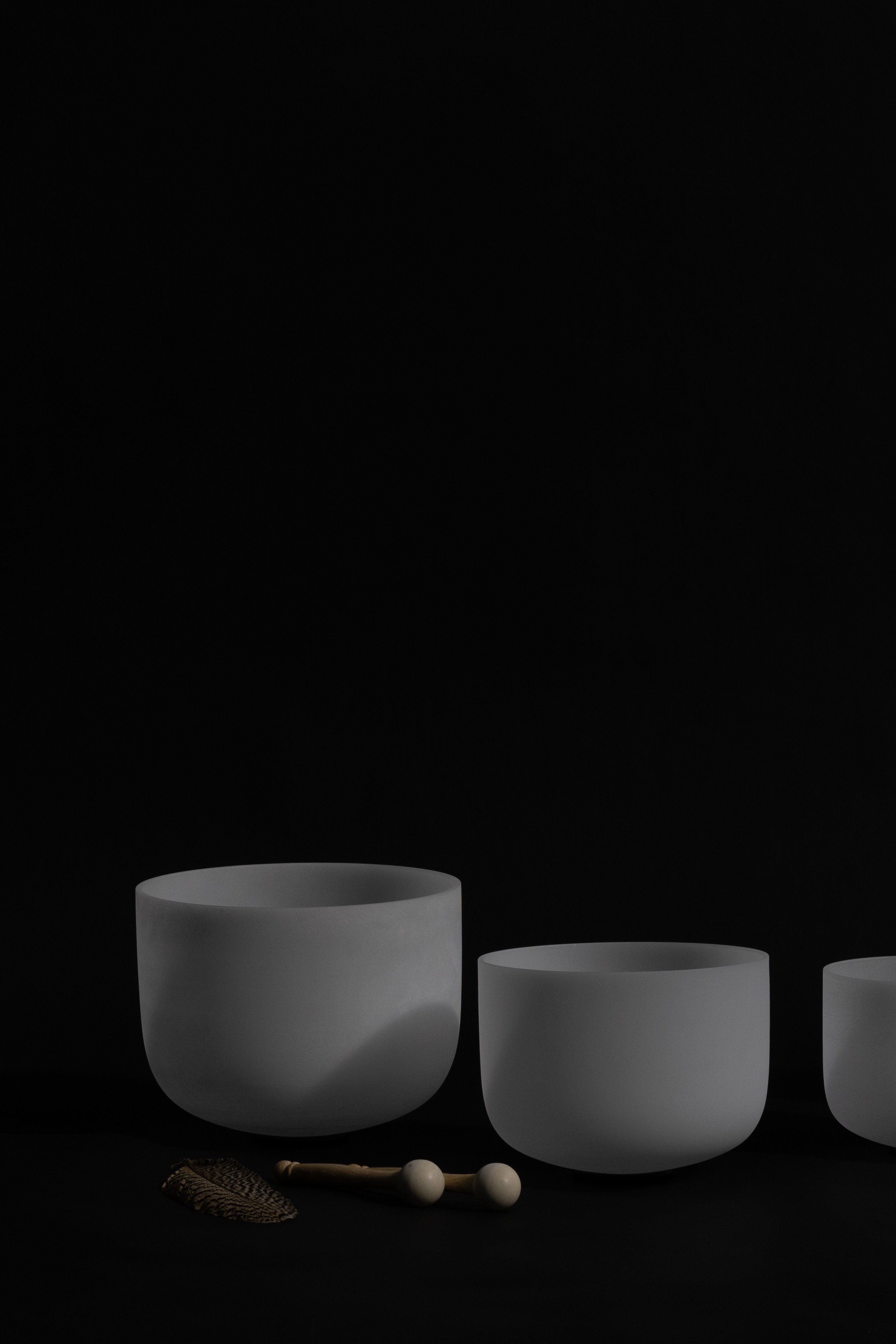 Two white sound bowls on black background with two wooden mallets in front, representing a healer’s spiritual space supported by a virtual assistant for digital product launches, content marketing, SEO, and admin.