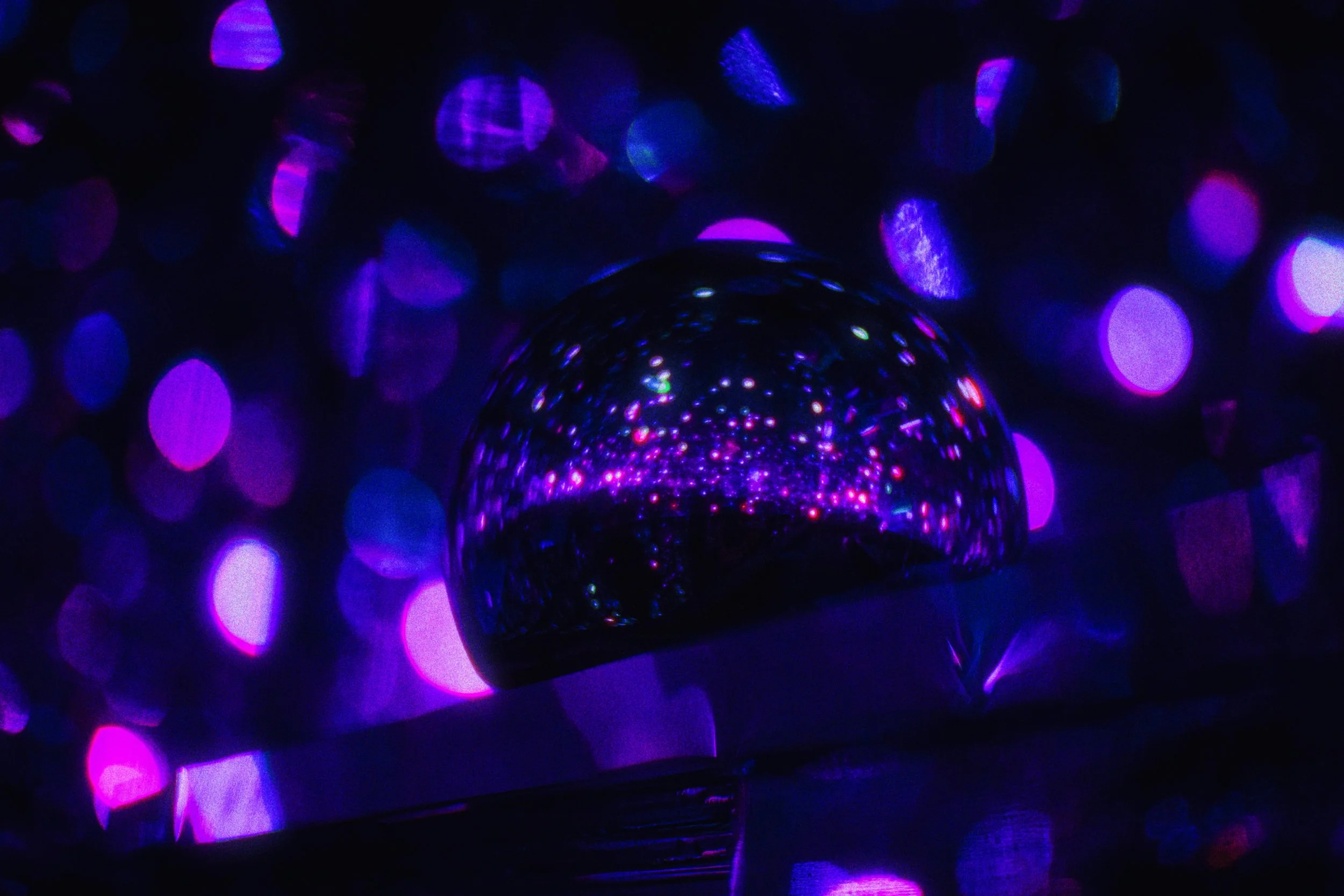 A mirrored disco sphere reflecting scattered points of colored light against a bokeh backdrop, echoing content that keeps showing up wherever people are looking