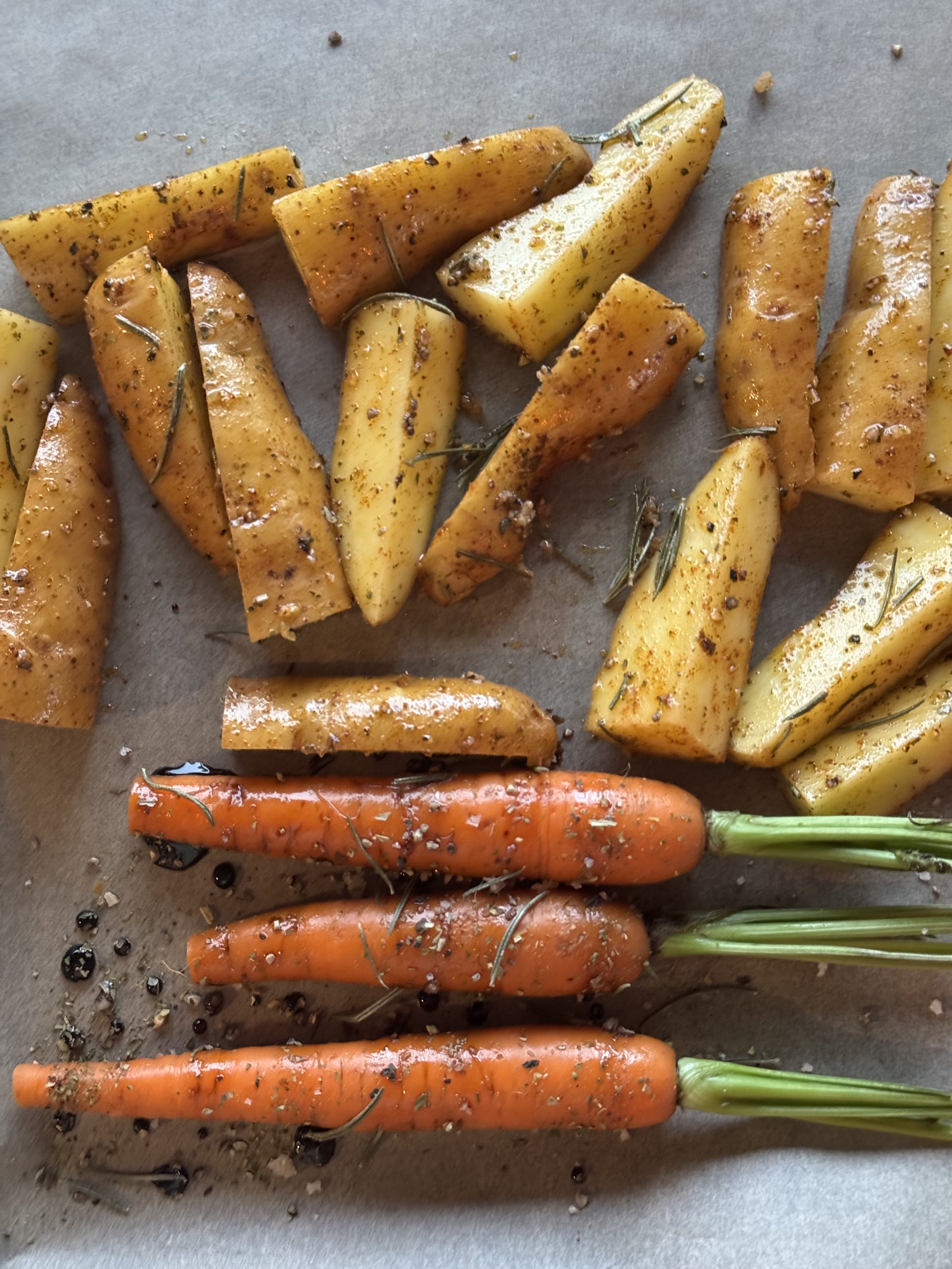 Close-up view of roasted potatoes and carrots seasoned with olive oil and herbs, sed as healthy recipe imagery for nutritionists working with virtual assistants on content creation.