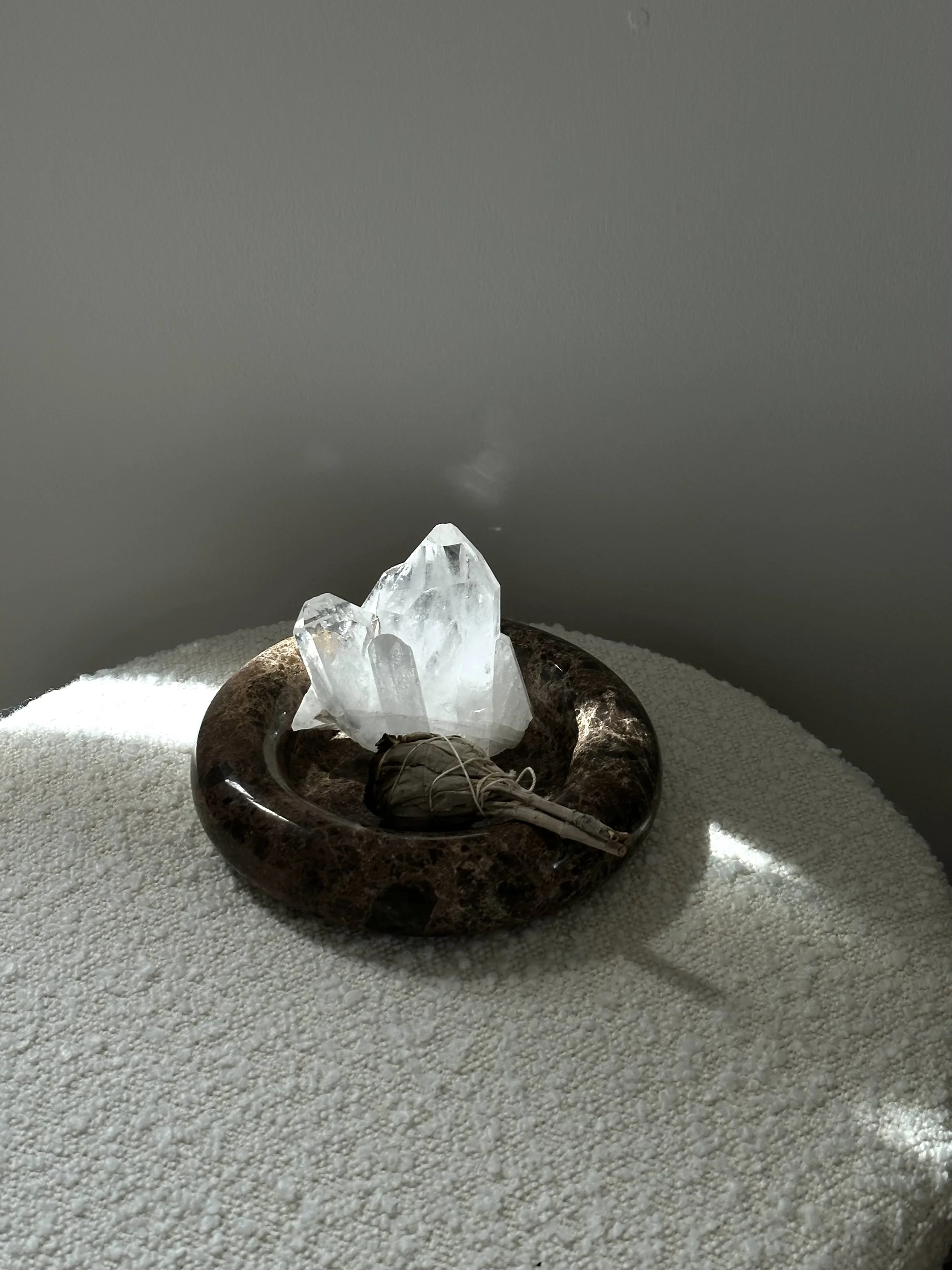 White chair seat with round brown marble dish holding a white crystal, representing a healer’s wellness space supported by virtual assistant services for digital product launches, content marketing, SEO, and admin.