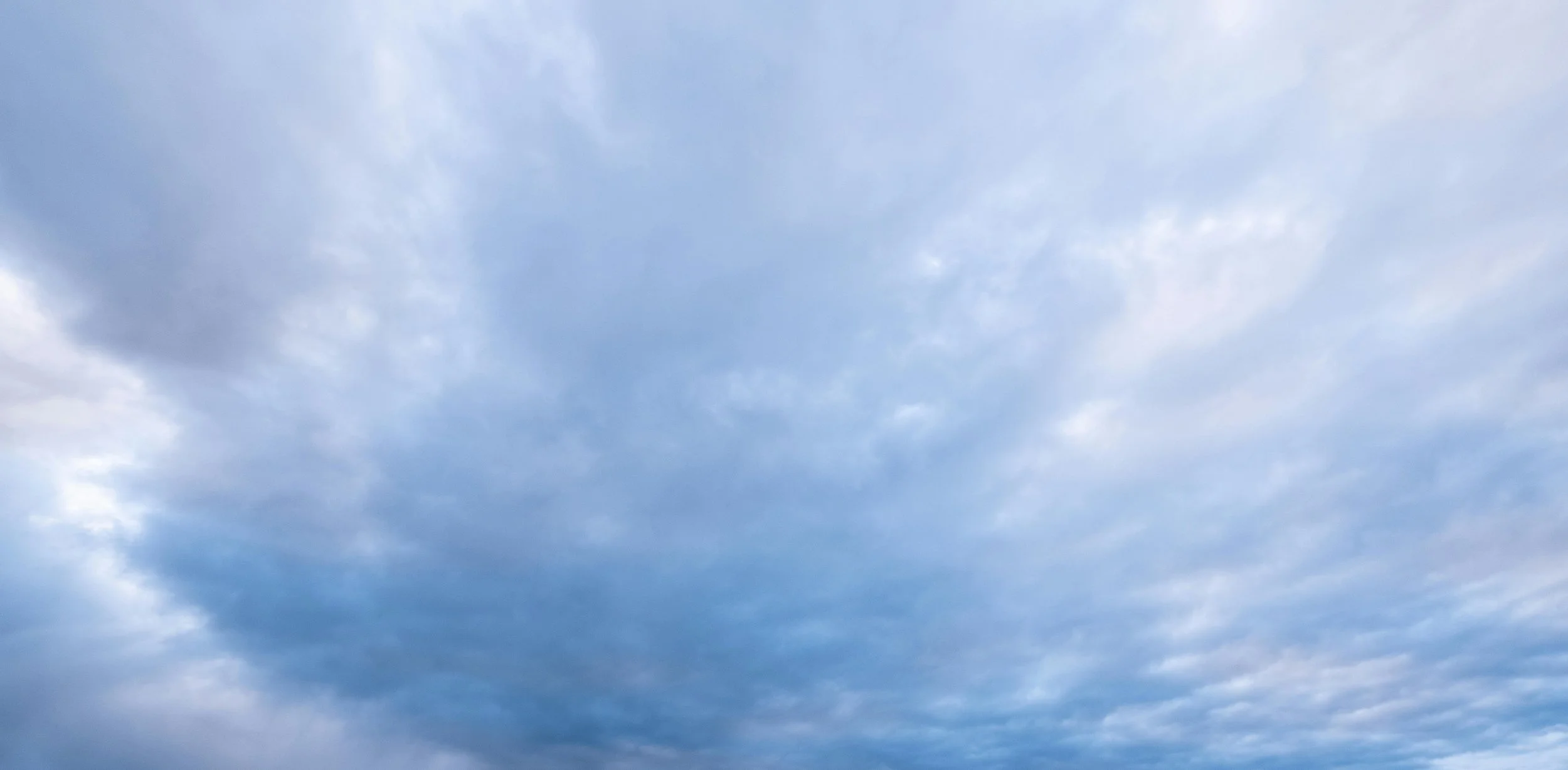 A wide, softly overcast sky in muted blue-grey, calm and even