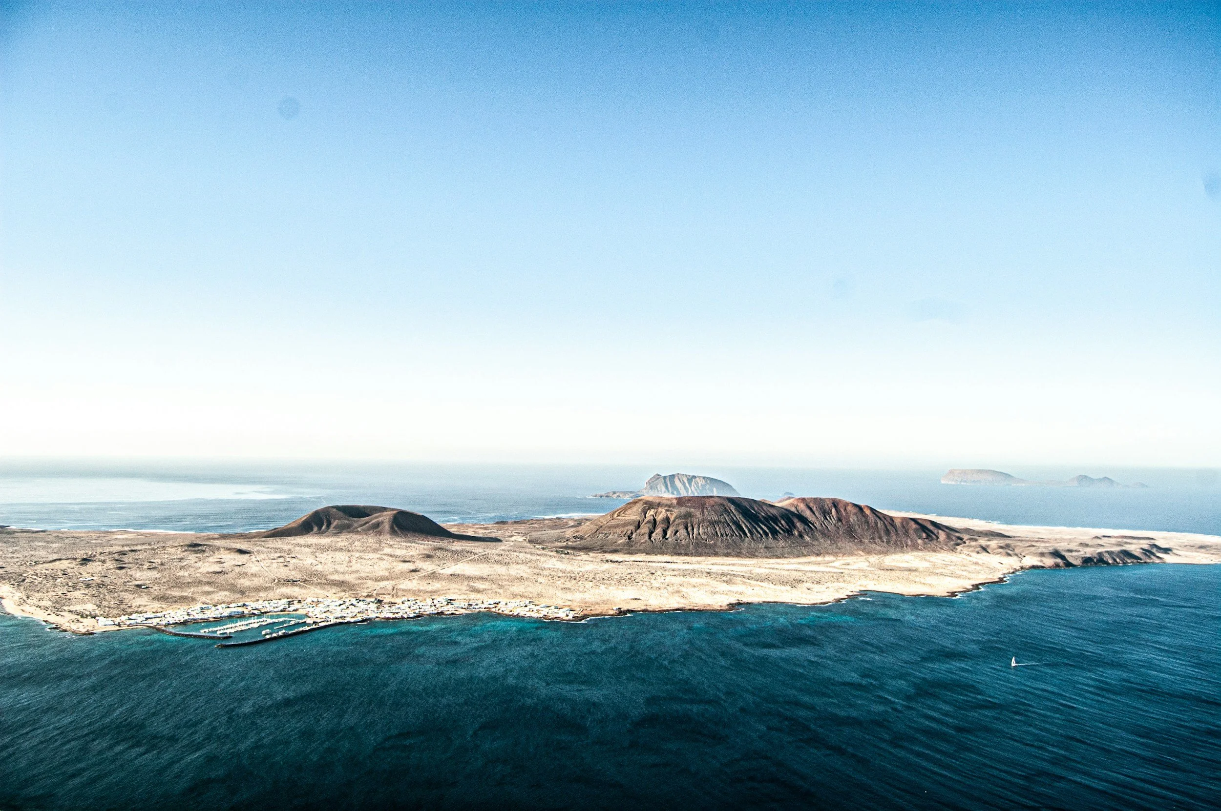 Landschaftsfoto mit schwarzem Sandstrand, grüner Lagune und Ozean, umgeben von vulkanischen Hügeln in El Golfo, Lanzarote, Spanien.