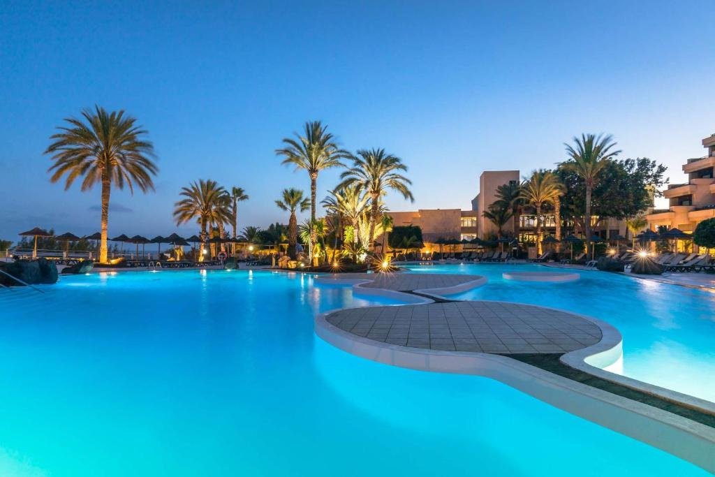 Hotelpool bei Sonnenuntergang mit Palmen