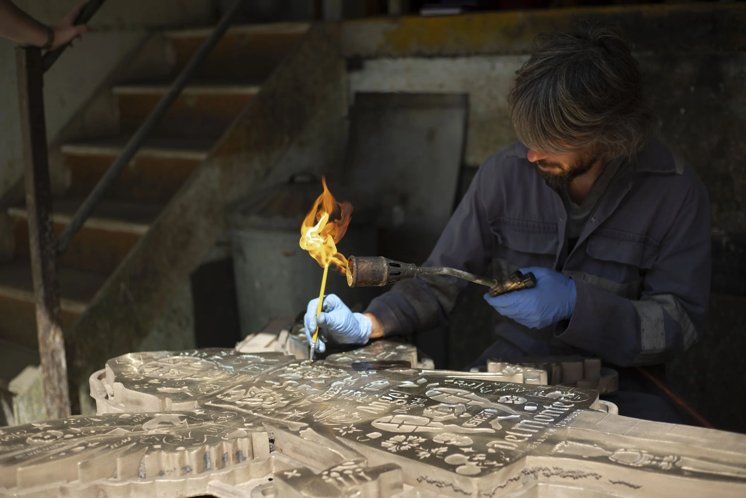 Close-up of a Pangolin Editions foundry specialist applying patina to Lhouette's Angel Cake bronze sculpture during the finishing process.