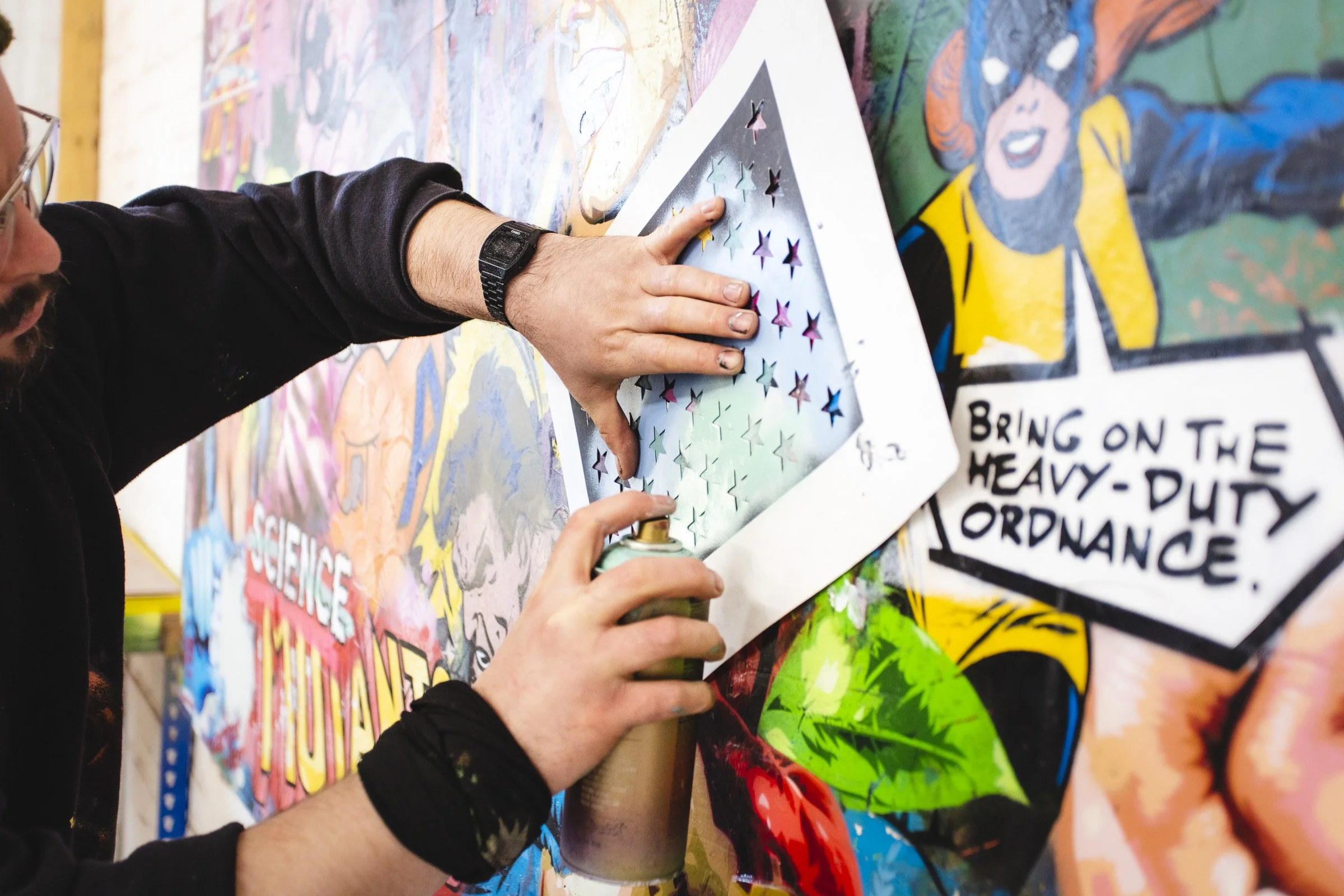 British contemporary artist Lhouette creating a bespoke mixed-media artwork using hand-cut stencils and aerosol paint in his studio.