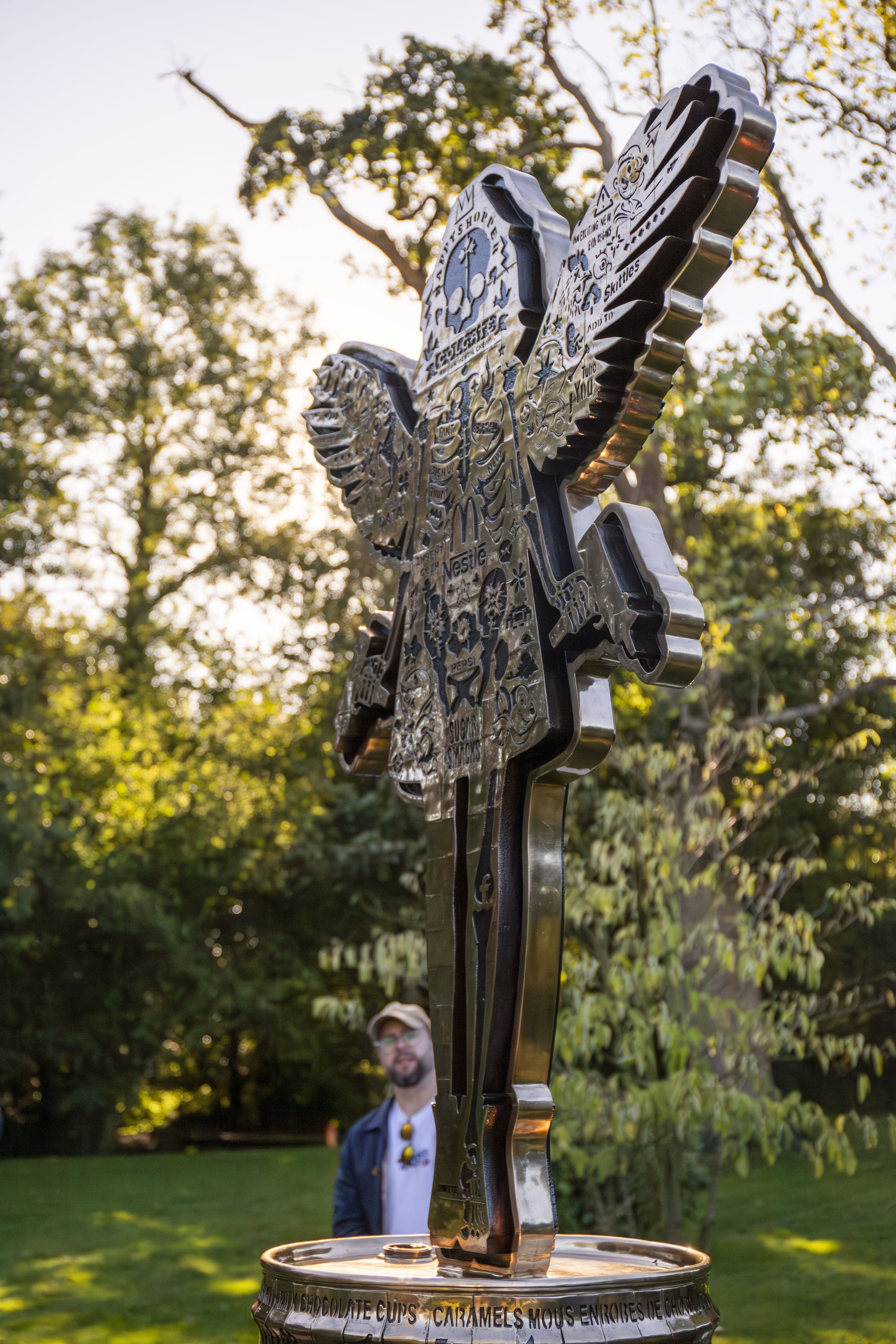 Side profile of Lhouette's monumental Angel Cake bronze sculpture, showing the depth of the winged figure and its cast bronze oil drum base.