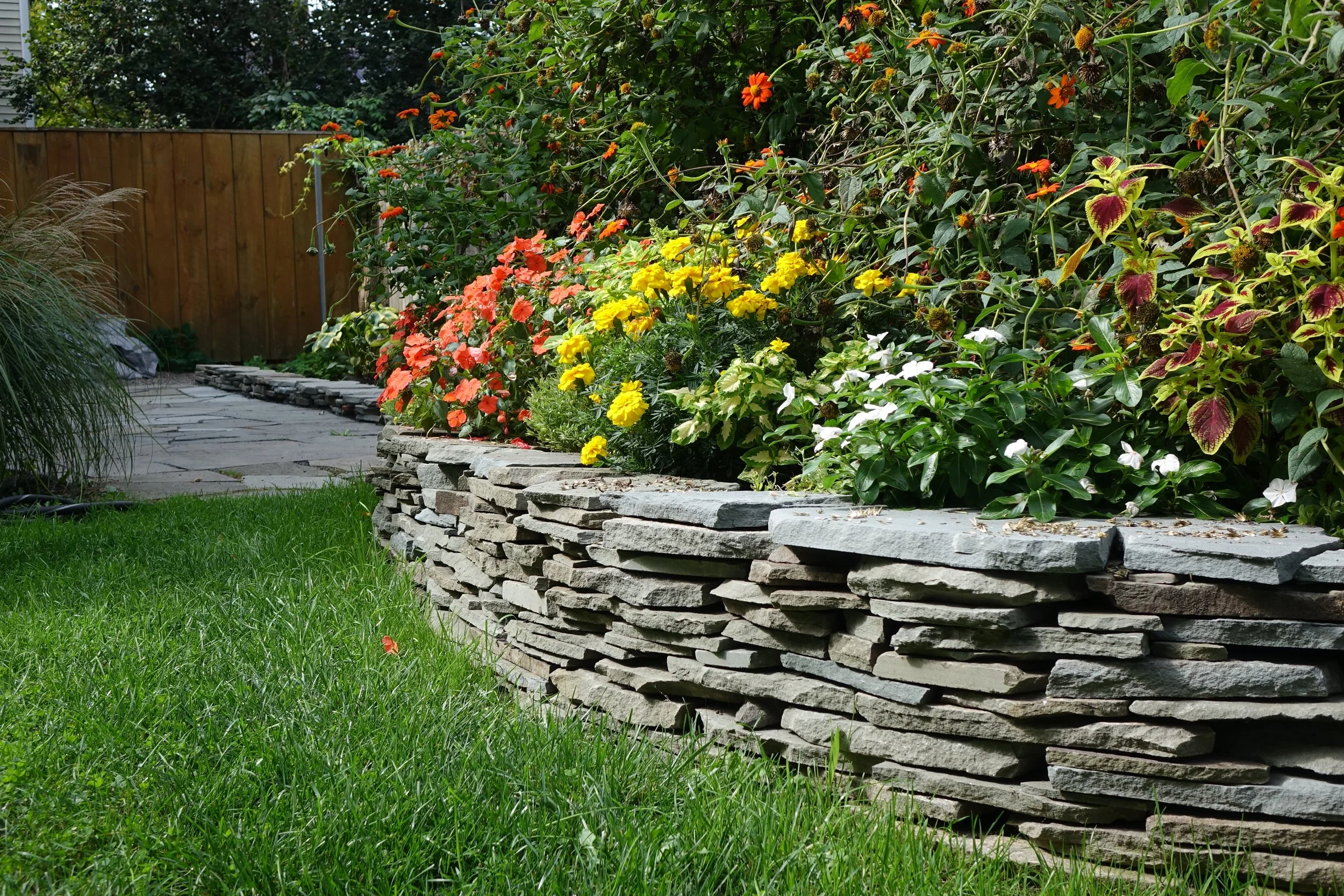 Stone garden bed and patio with flower plants.