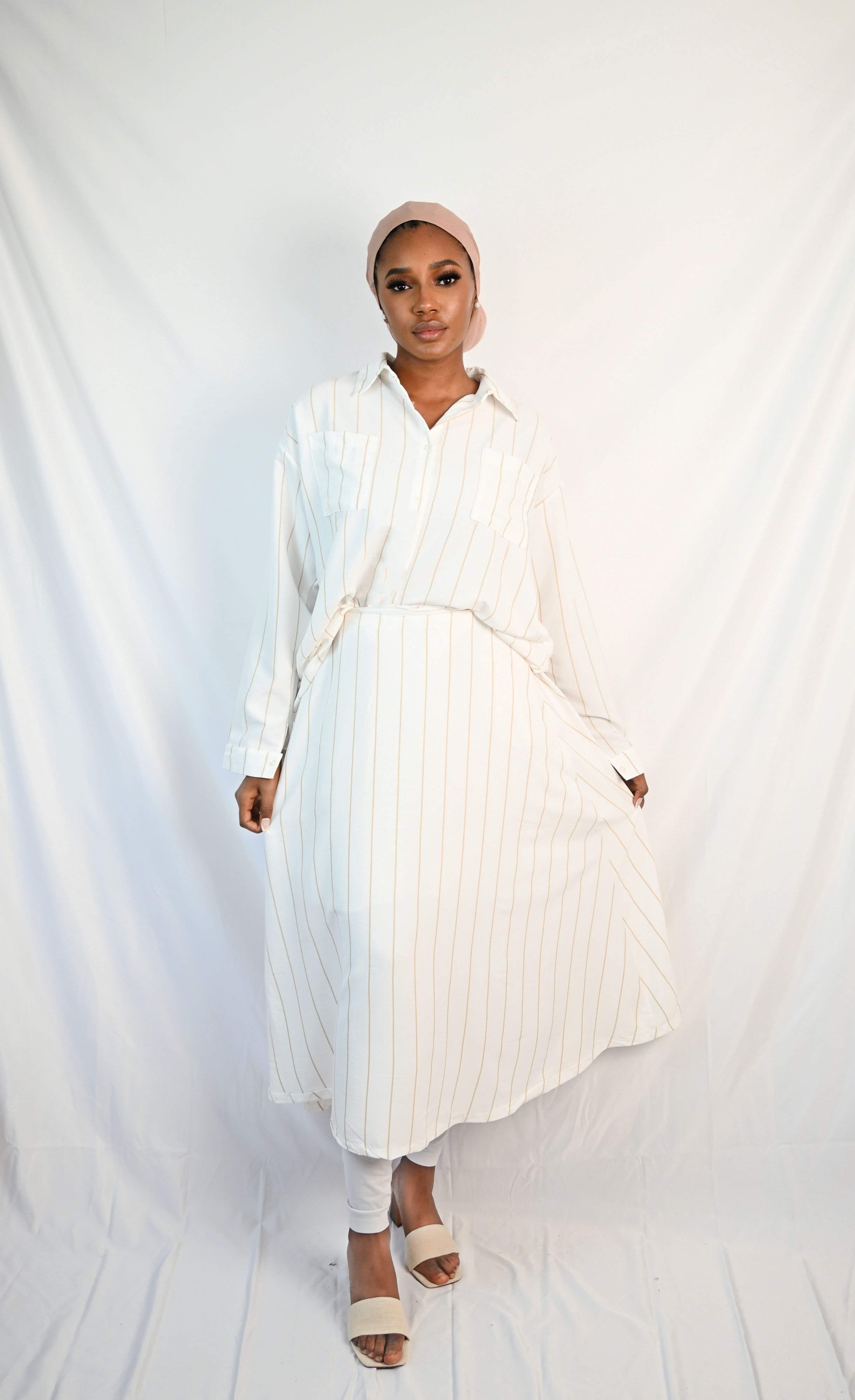 Frau trägt beige-gestreiftes Hemd mit passendem Rock, elegantes Set mit langen Ärmeln und fließendem Schnitt, perfekte Wahl für einen stilvollen, modernen Look.