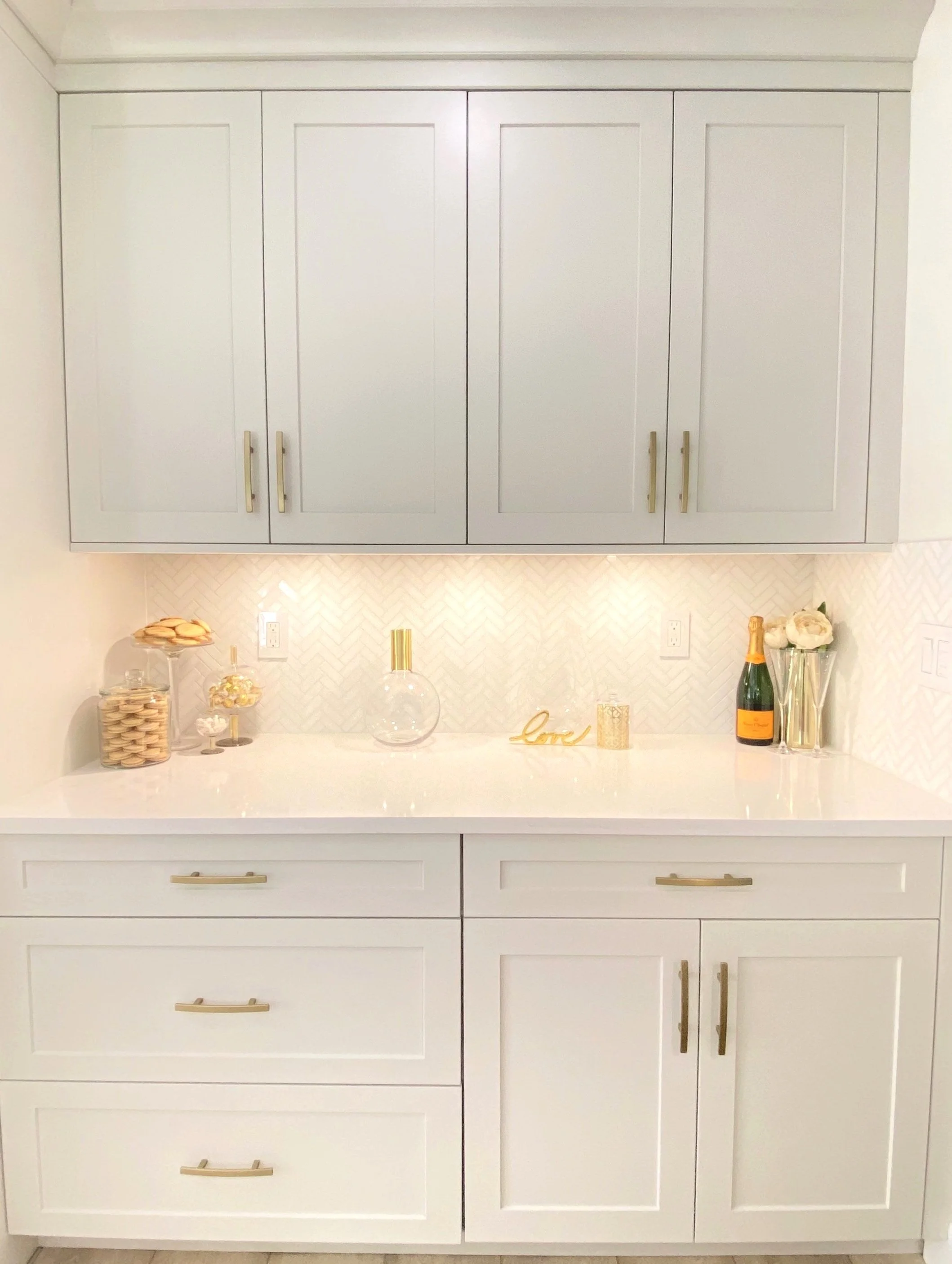 Timeless kitchen designed by Graham & Co. Interiors in Tampa, Florida, featuring warm white cabinetry, white marble backsplash, and elegant brass finishes.