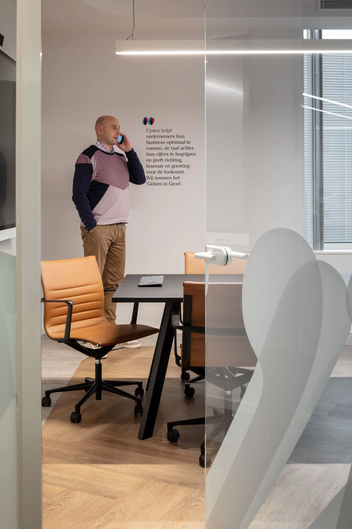 Mooie interieurarchitectuur door MAMU Architecten. Man met gsm in bureau.