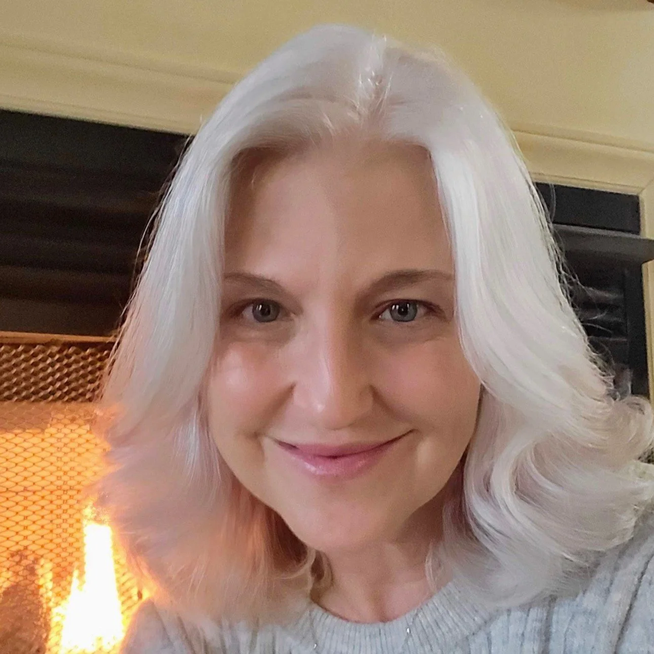 Headshot of Angela Harris smiling at the camera with a fireplace in the backgrond