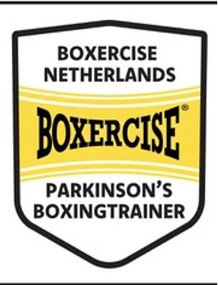 A logo for Boxercise Netherlands, featuring the words 'Boxercise Parkinson's Boxingtrainer' with a yellow banner and black text on a shield-shaped background.